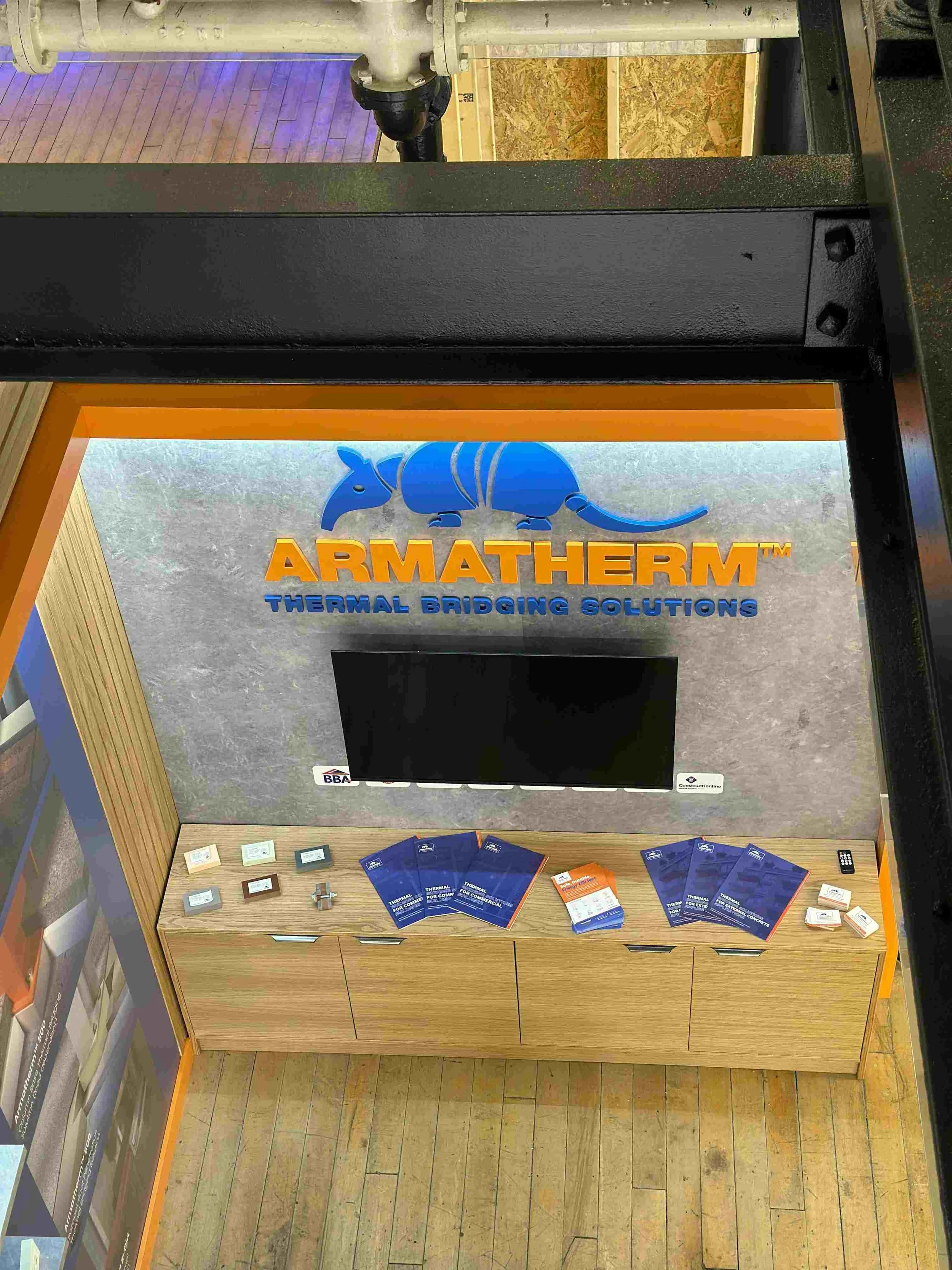 Armatherm product display area with branded wall graphics, TV screen and thermal bridging product samples