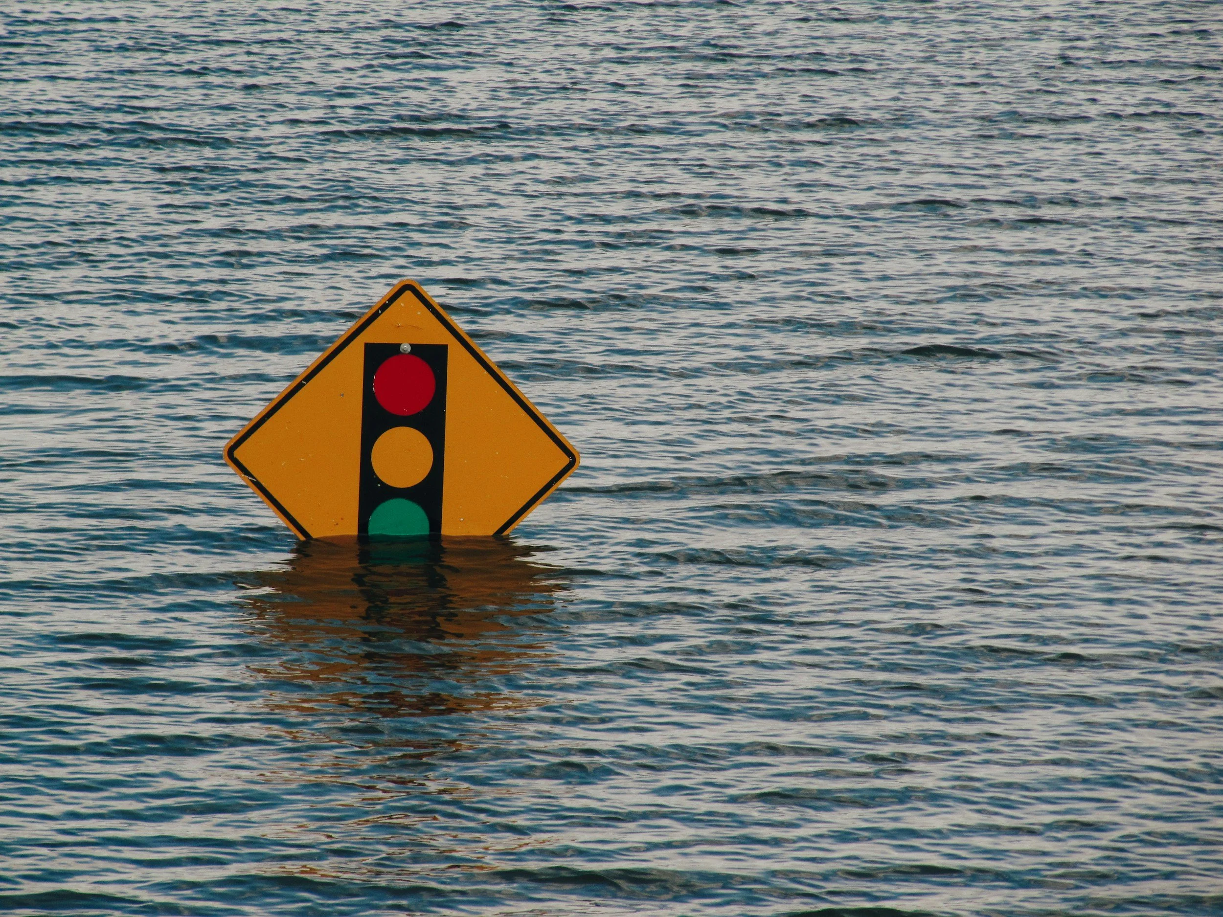 A traffic light sign partially submerged in water.