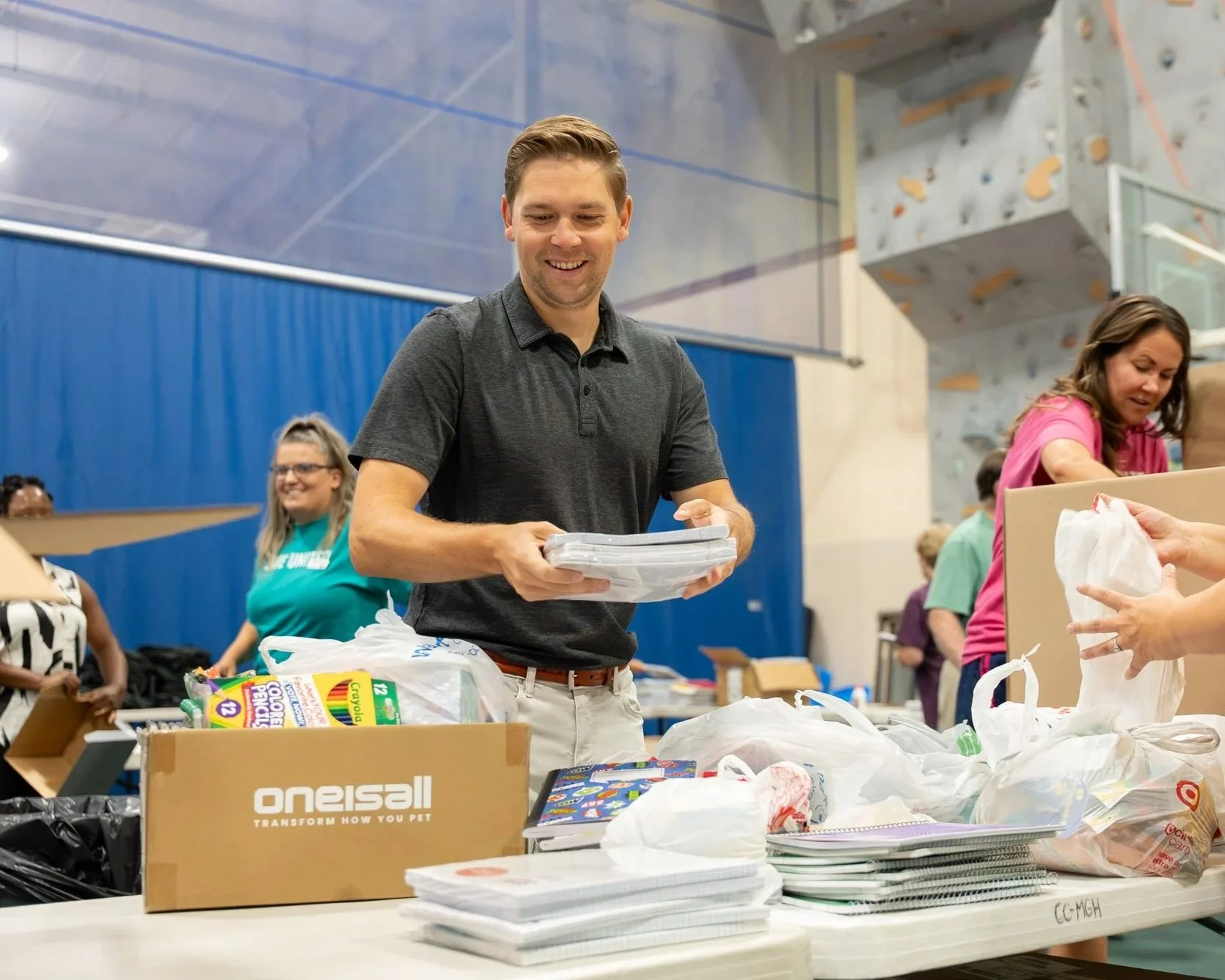 People volunteering at a school donation event, organizing boxes and items on tables.