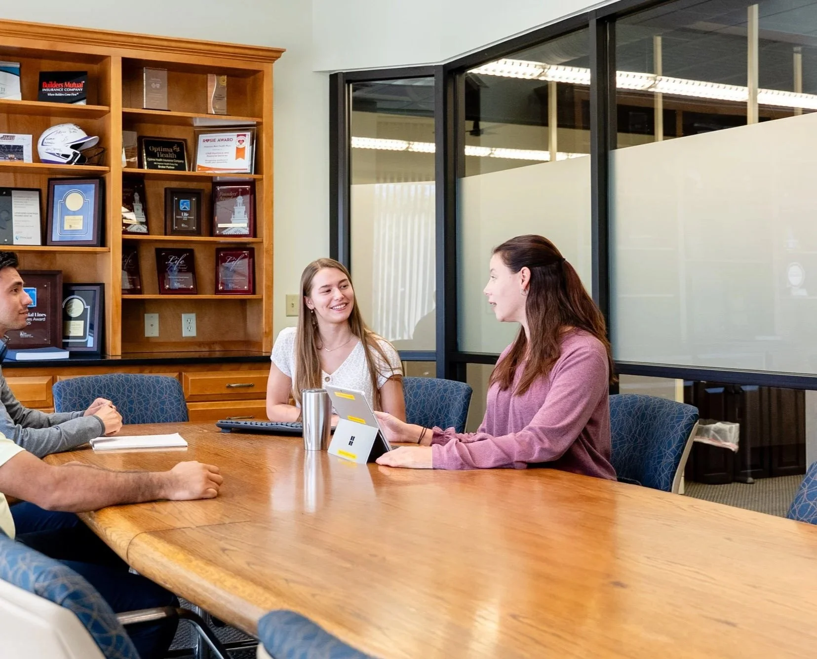 Group of people having a meeting in a conference room, with a woman speaking to others.