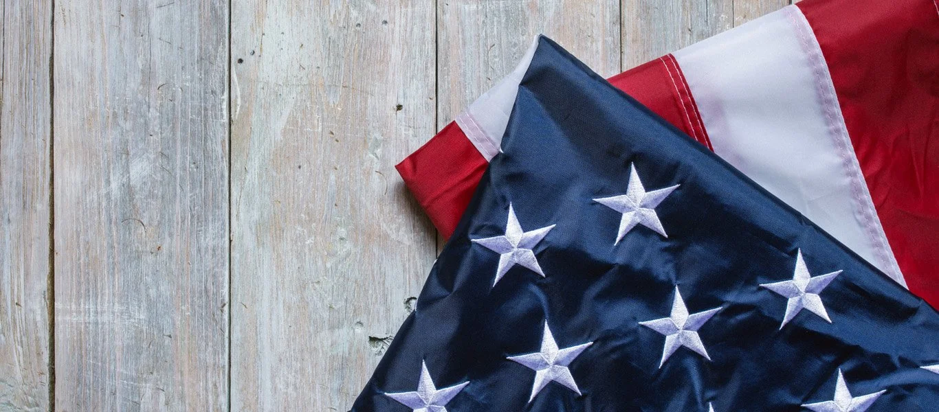 Part of two folded American flags on a wooden surface.