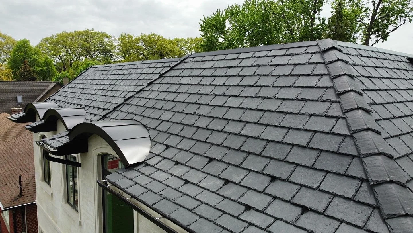A house with a Davinci composite slate roof, flat lock metal panels on a barrel dormer roof.