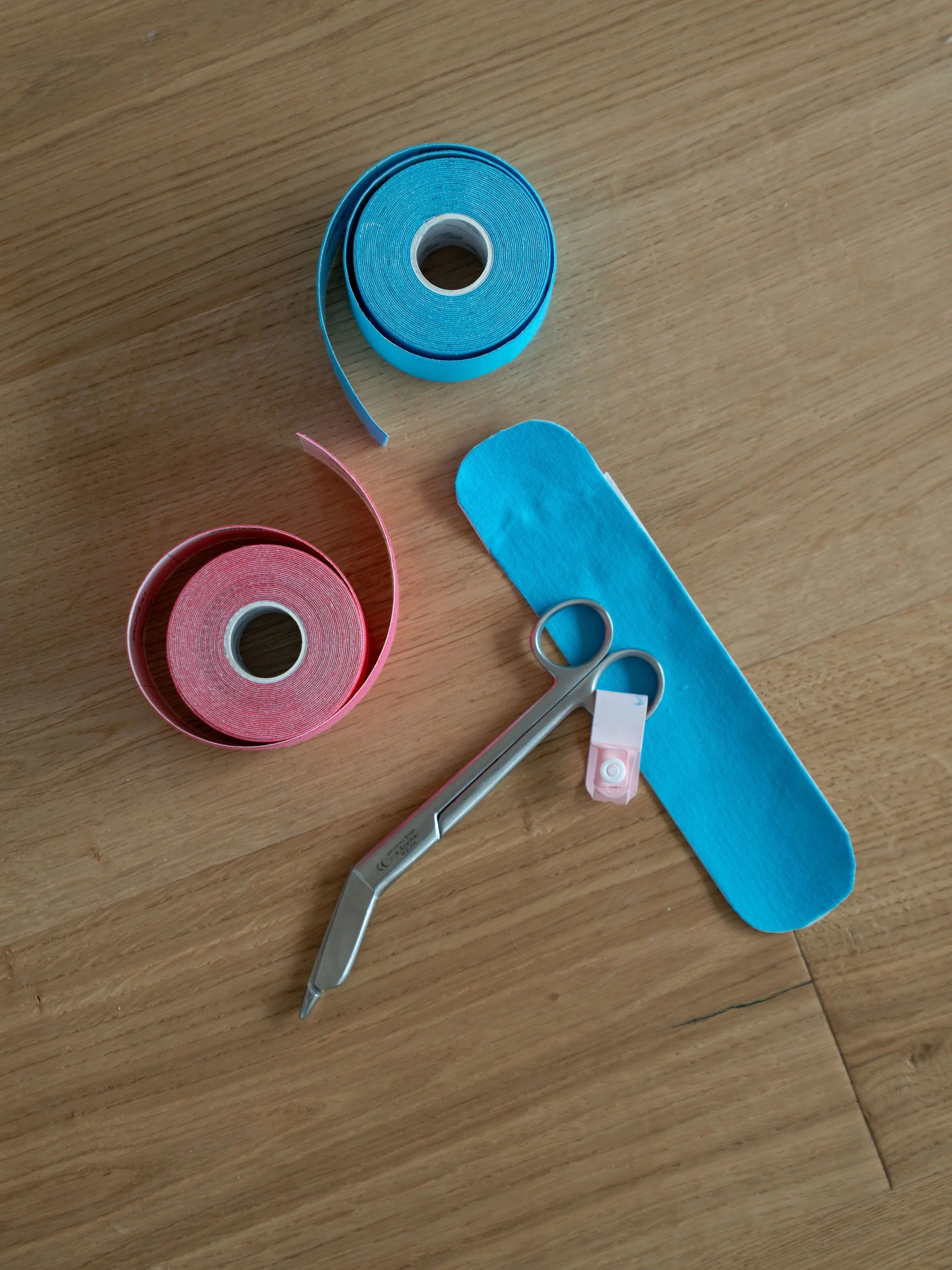 rosa und blaues kinesiologisches Tape  auf Holztisch, Schere