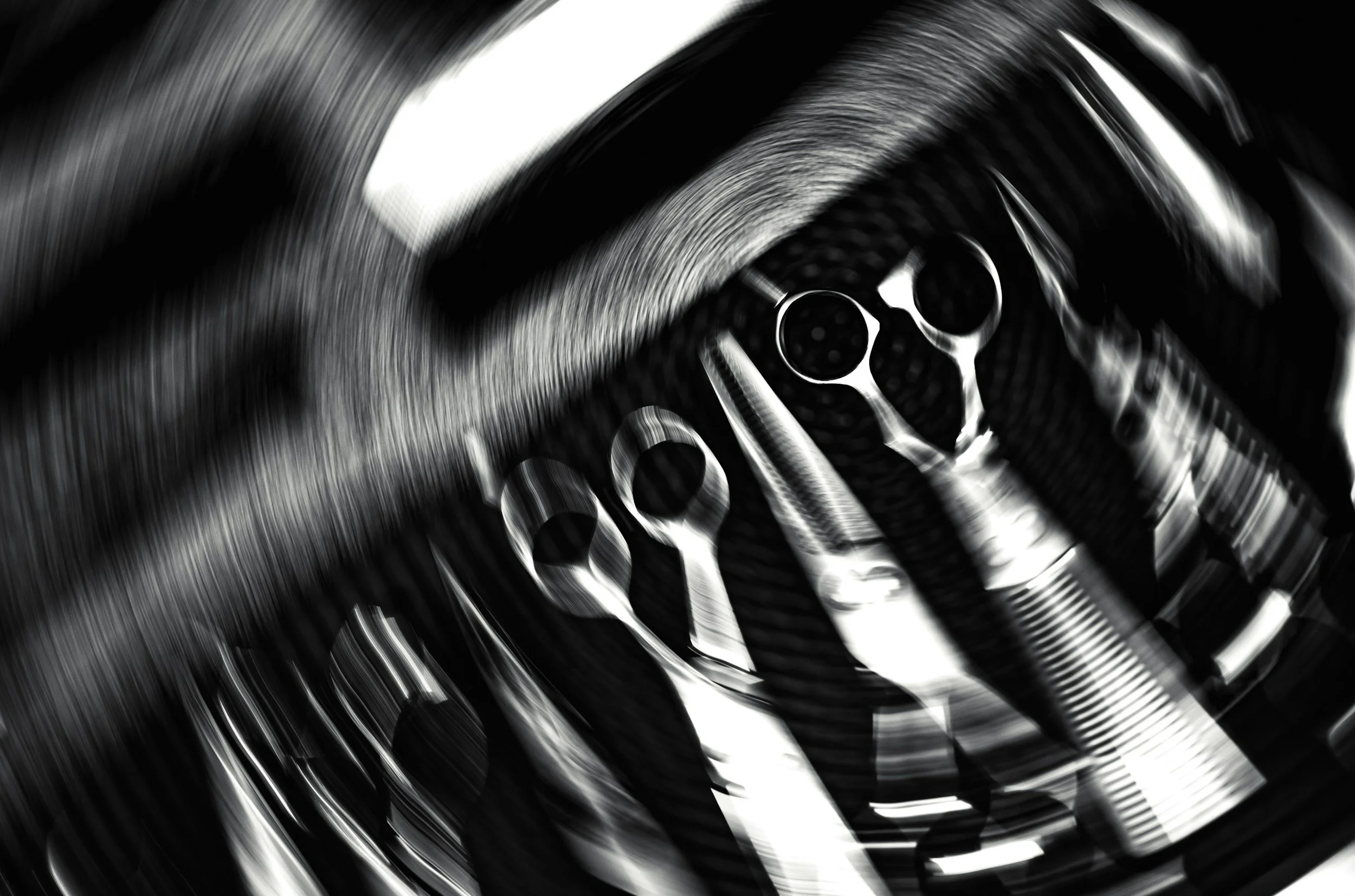 Close-up of a mechanical component with cylindrical holes, rendered with motion blur in black and white.