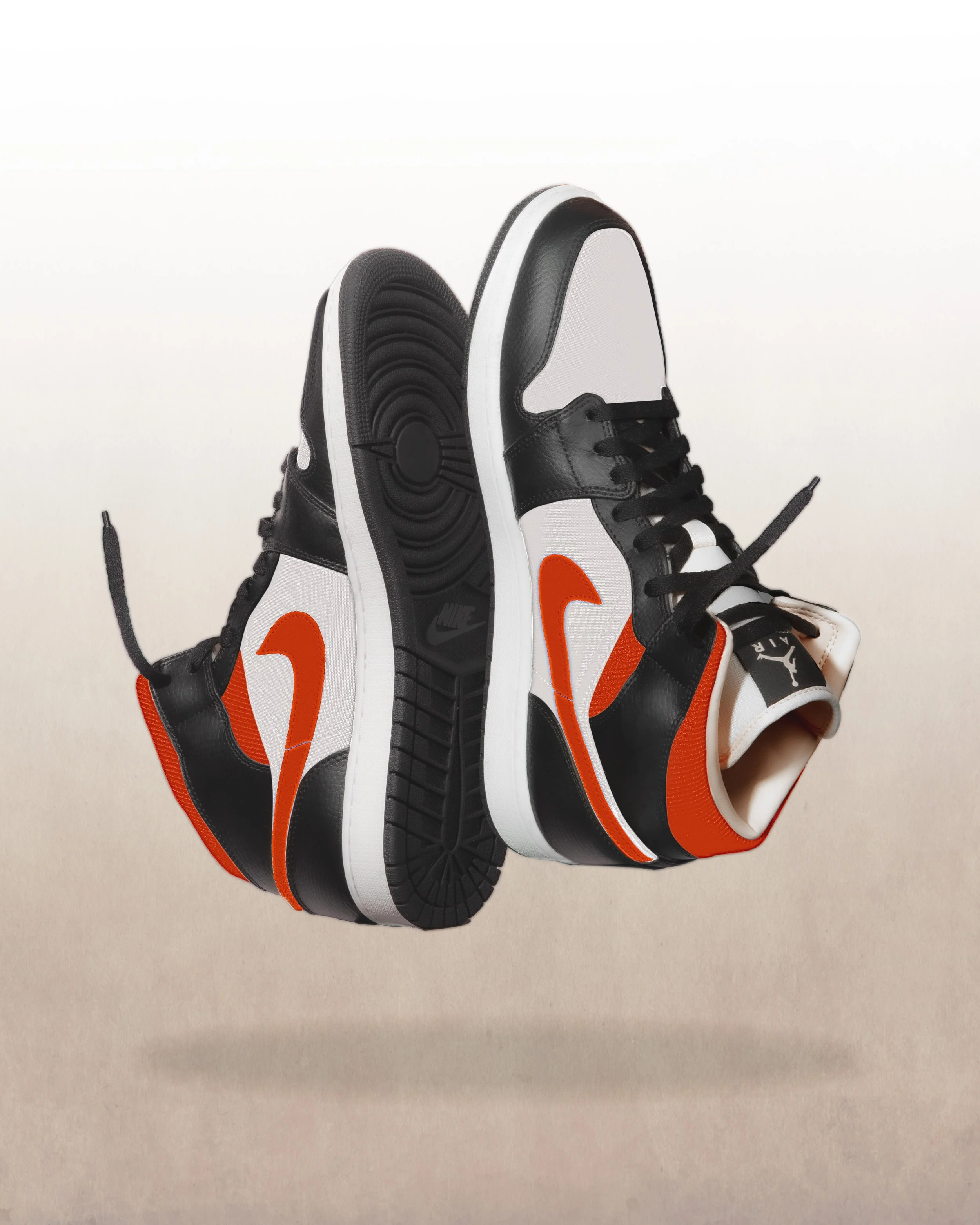 Pair of Nike sneakers in black, white, and orange, floating against a neutral background.