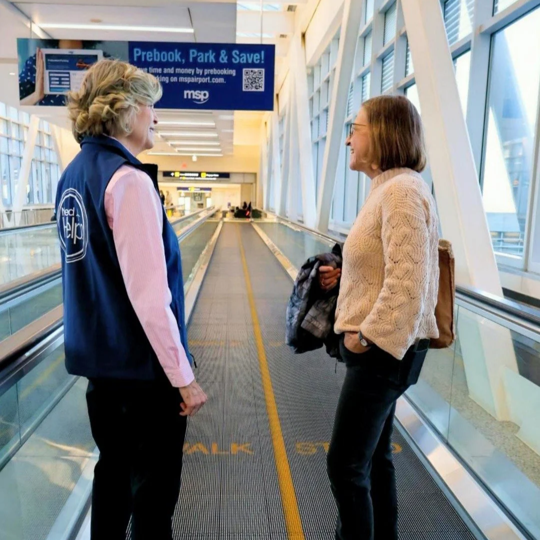 Femail volunteer in blue vest helping a traveler on a moving walkway