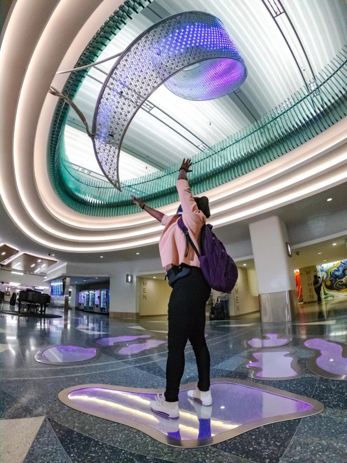 Women standing underneath the Aurora Art piece on the Arrivals level of MSP Airport