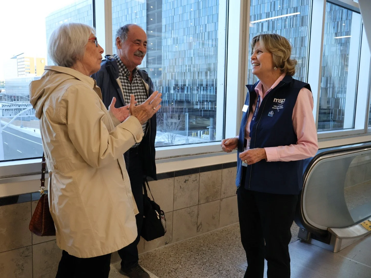 Volunteer standing with two travelers and laughing