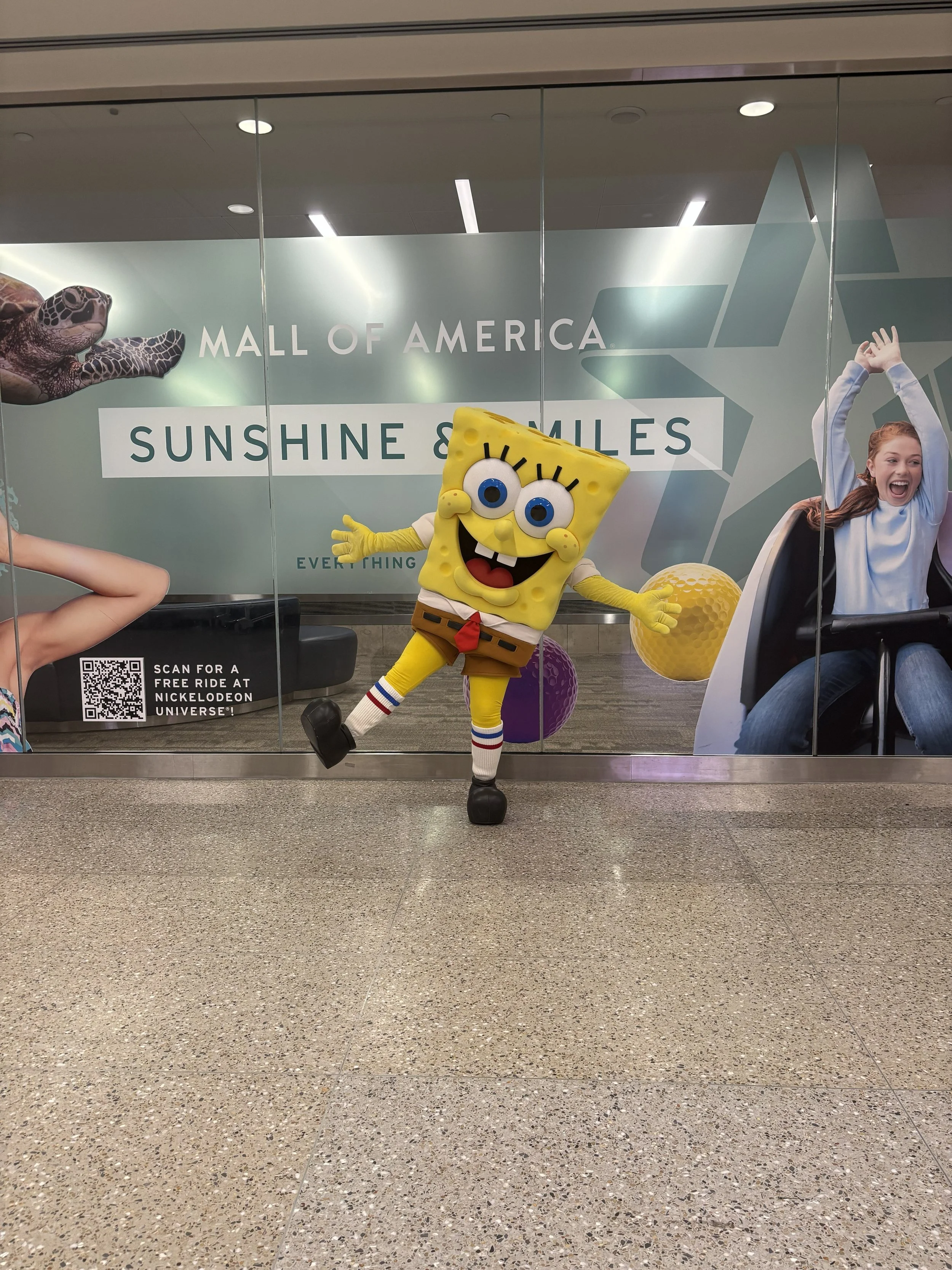 Mall of America SpongeBob Mascot posing outside of their Spring Break Activation that says "Mall of America Sunshine & Smiles"