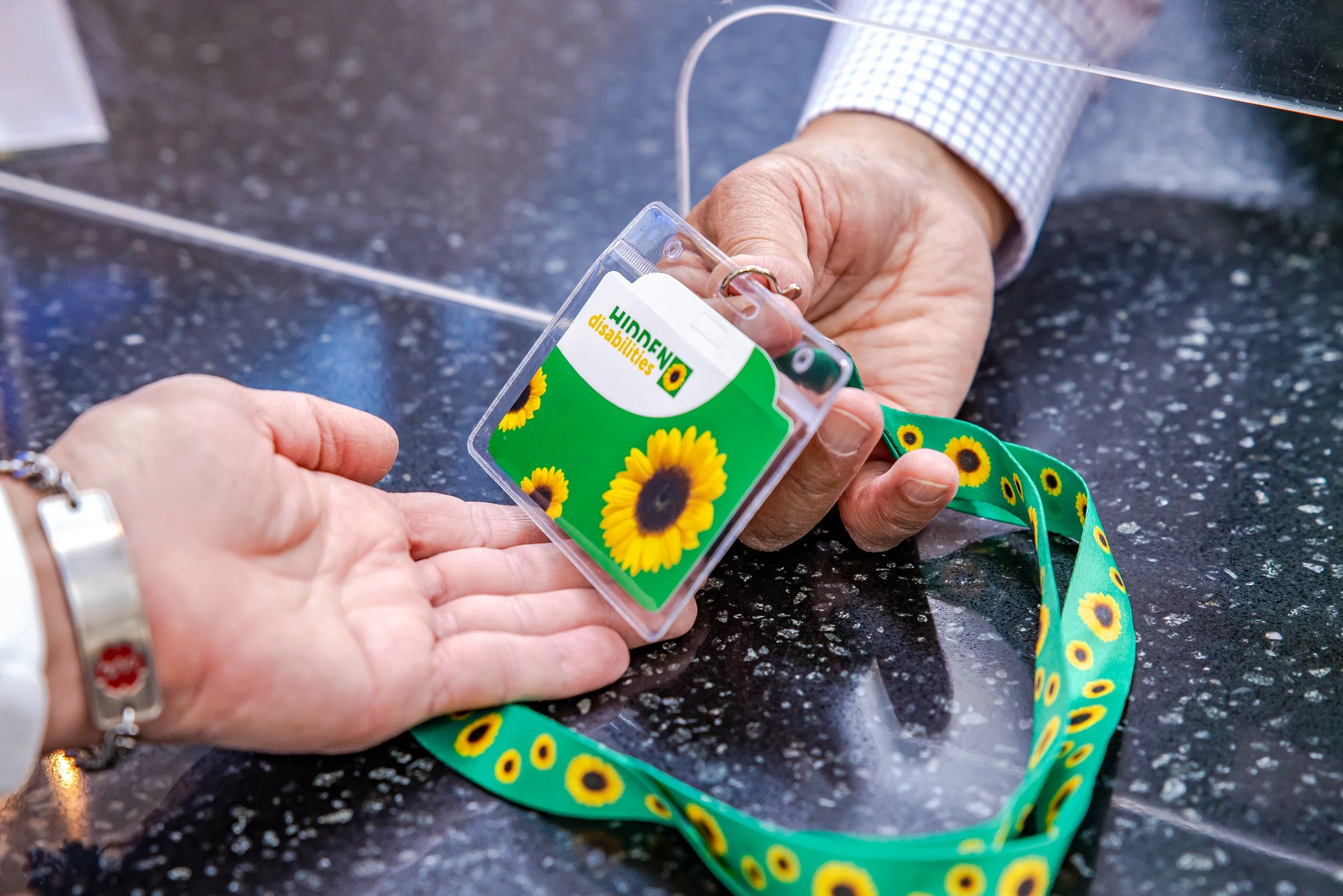Hidden Disabilities Sunflower Program Lanyard being handed to a traveler