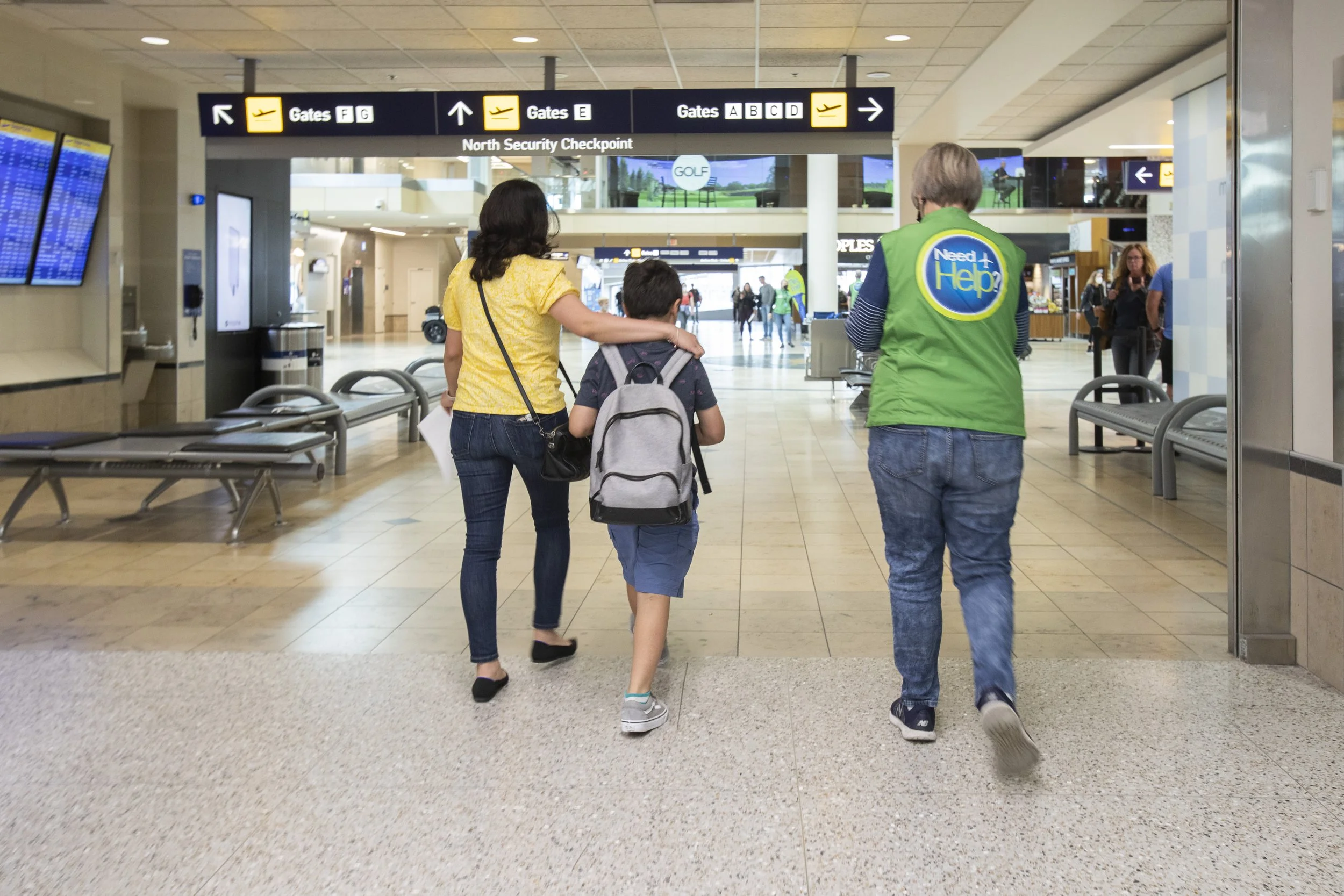 Volunteer walking and helping a mother and son through the airport
