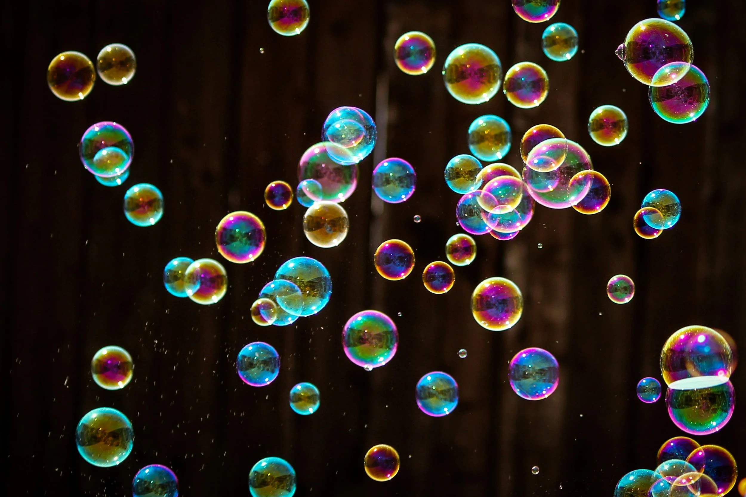 Colorful soap bubbles floating against a dark background.