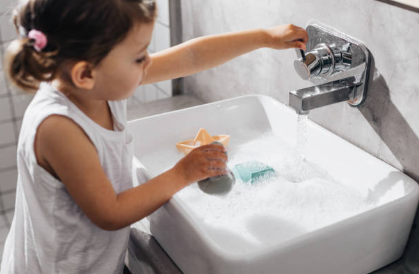 A young child with glasses sitting on a potty in a tiled bathroom.