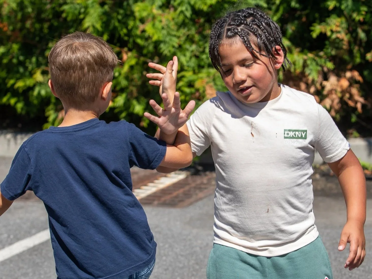 A young girl spinning and dancing on a grassy field at sunset, wearing a light blue dress with pastel patterns, with trees and a creek in the background.