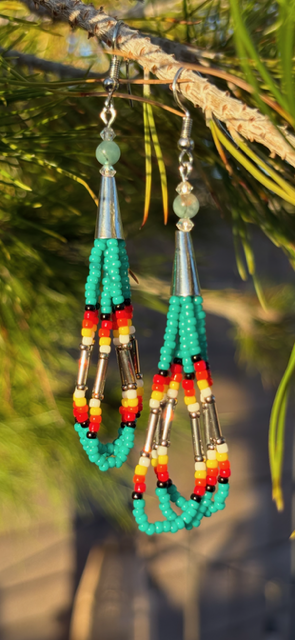 Beaded earrings hanging from a branch, featuring turquoise, red, yellow, white, and silver beads with cone-shaped silver caps.