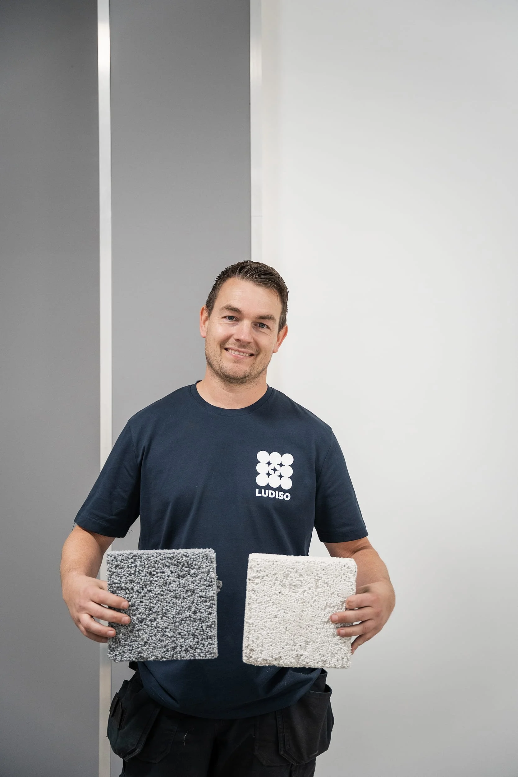 Employé de Ludiso présentant deux échantillons d’isolation contenant des billes EPS grises et blanches.