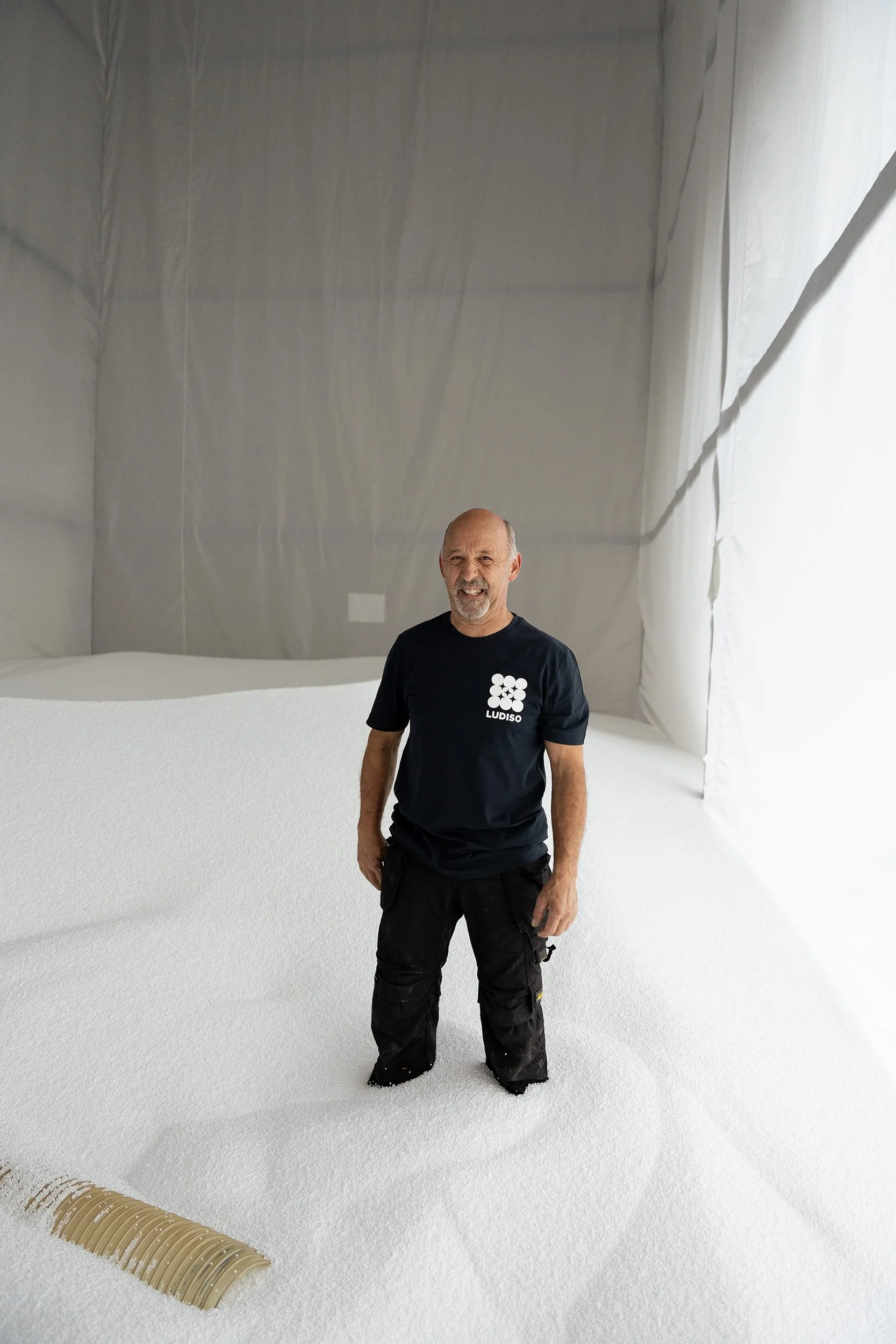 Employé de Ludiso dans un grand espace de stockage rempli de billes isolantes blanches destinées à l’isolation thermique.