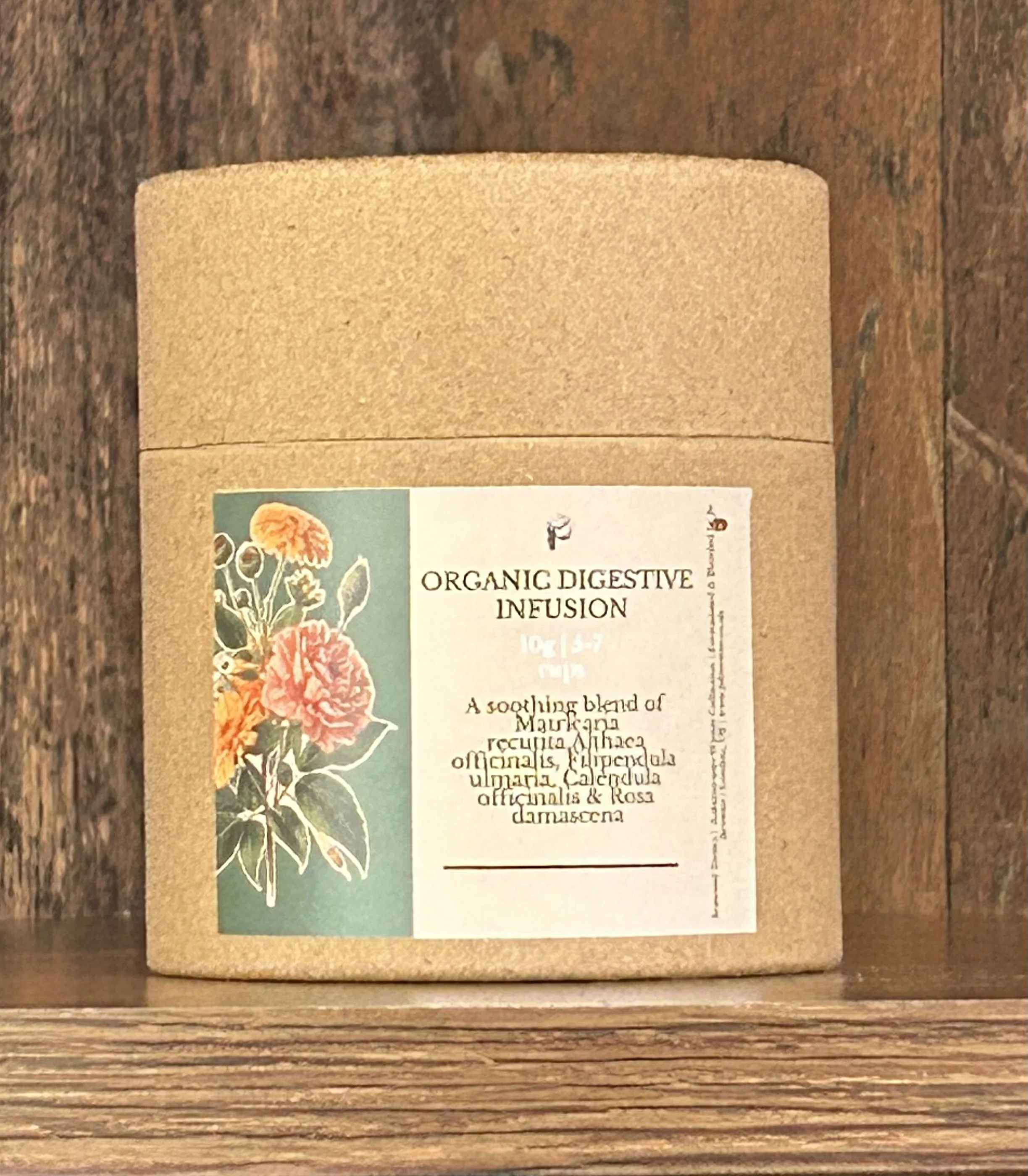 A cardboard container with a label reading 'Organic Digestive Infusion' and a floral illustration on the left side.