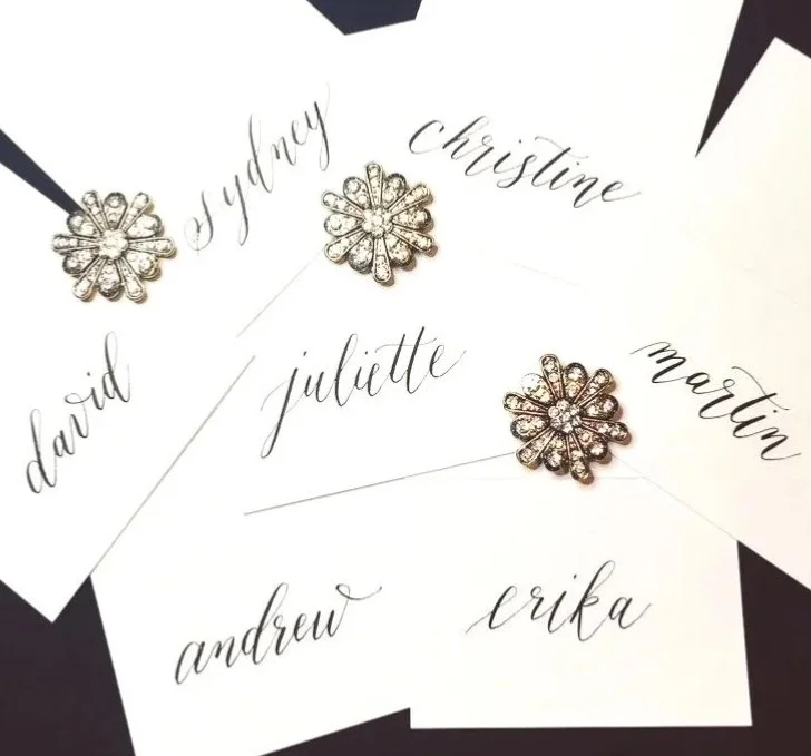 Name cards with cursive names: David, Sydney, Christine, Martin, Juliette, Andrew, Erika, under decorative silver pins.
