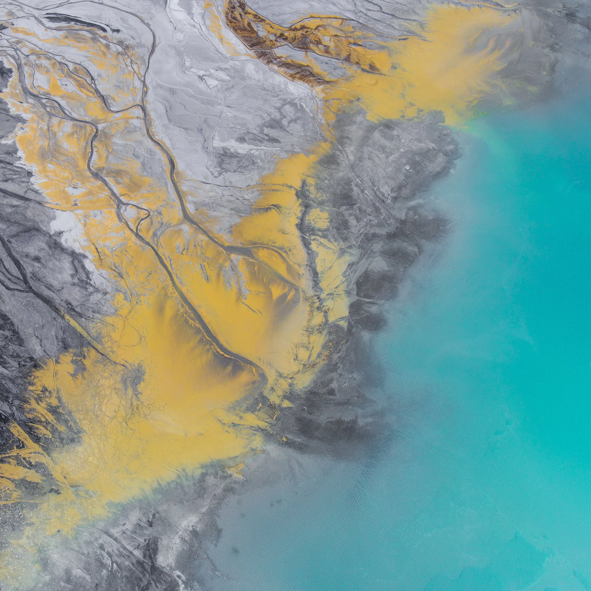 Aerial view of a golden coastal landscape with rugged mountain formations and turquoise water, representing depth, perspective, and balance in executive bio development.