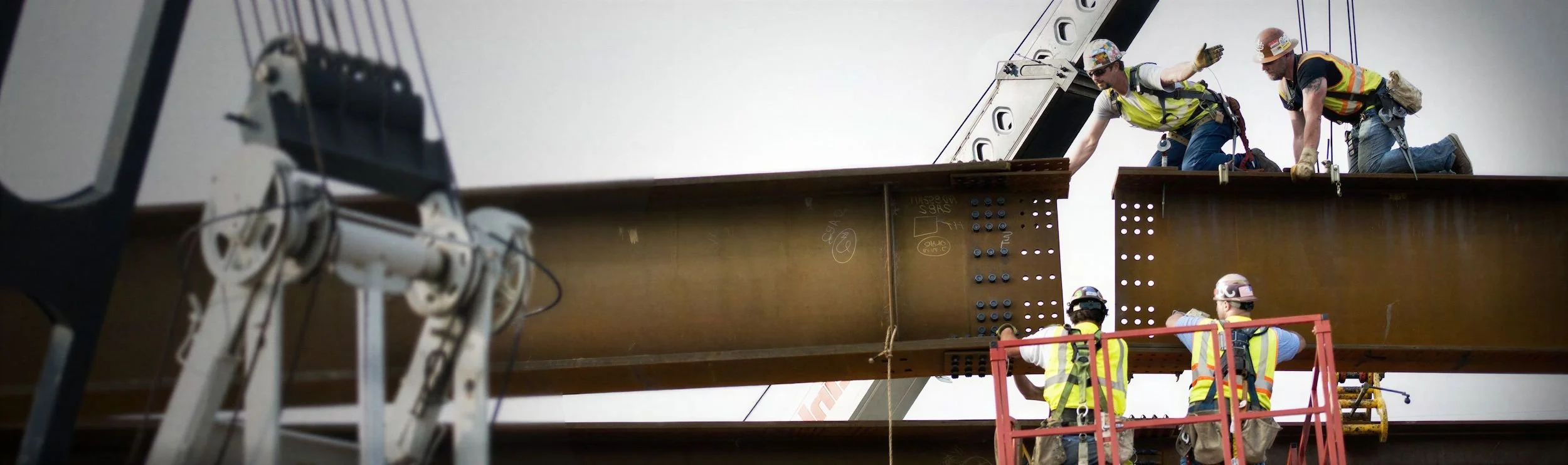 Ironworkers connecting a structural steel beam during a crane-assisted commercial erection
