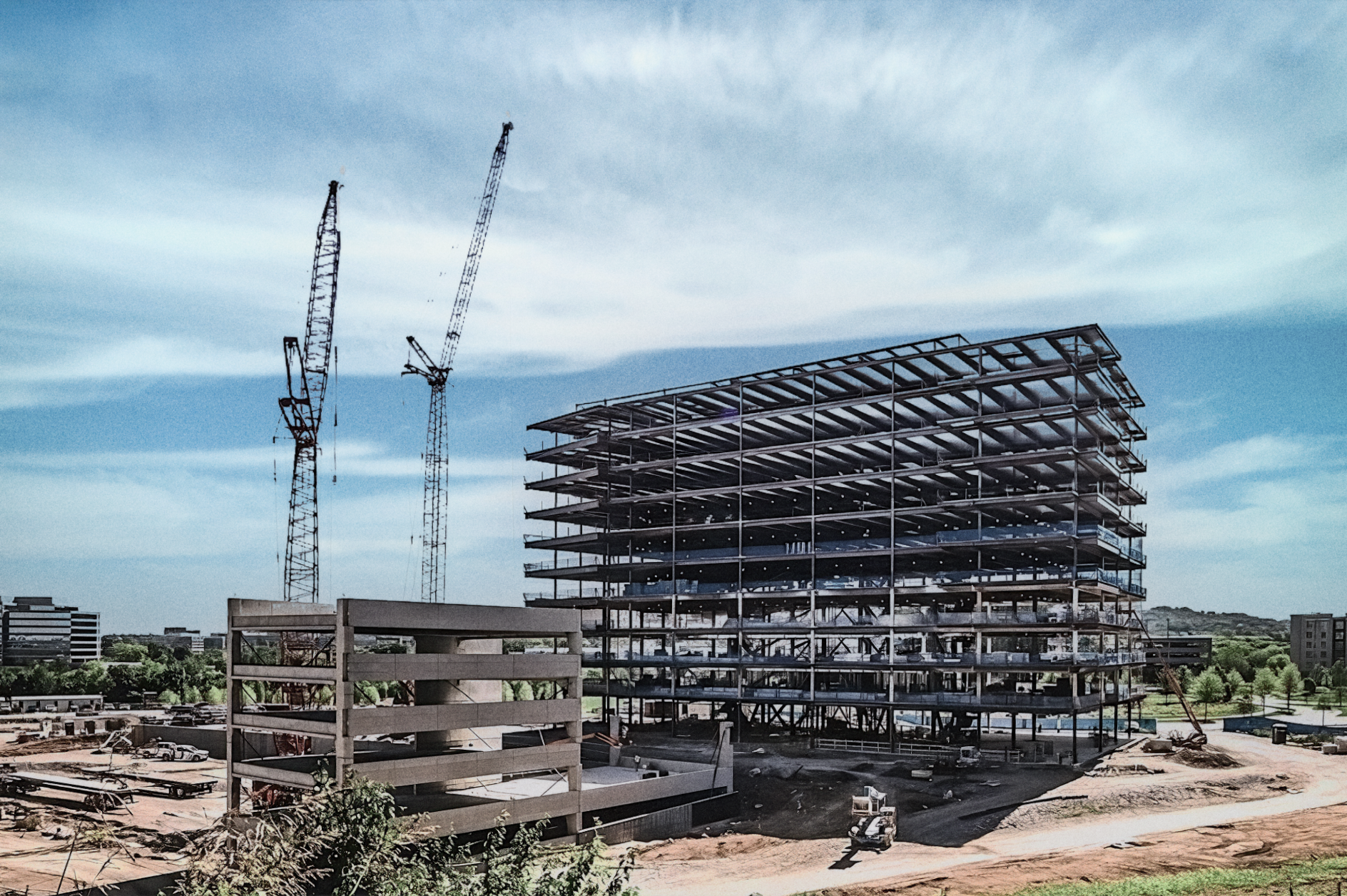 Steel-frame commercial office building under construction with cranes on site in Nashville, TN, showcasing large-scale development and modern engineering.