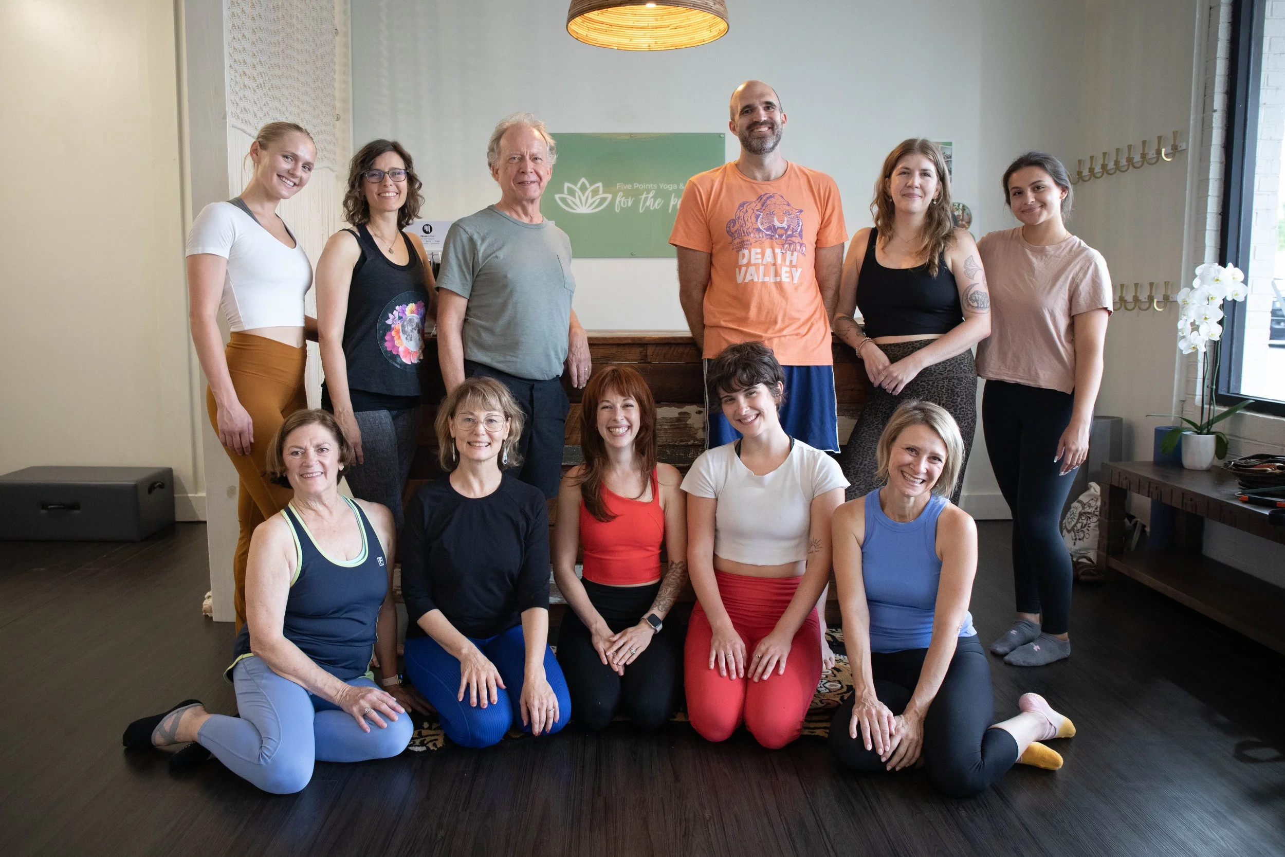 Group photo of instructors smiling in front of the front desk and logo