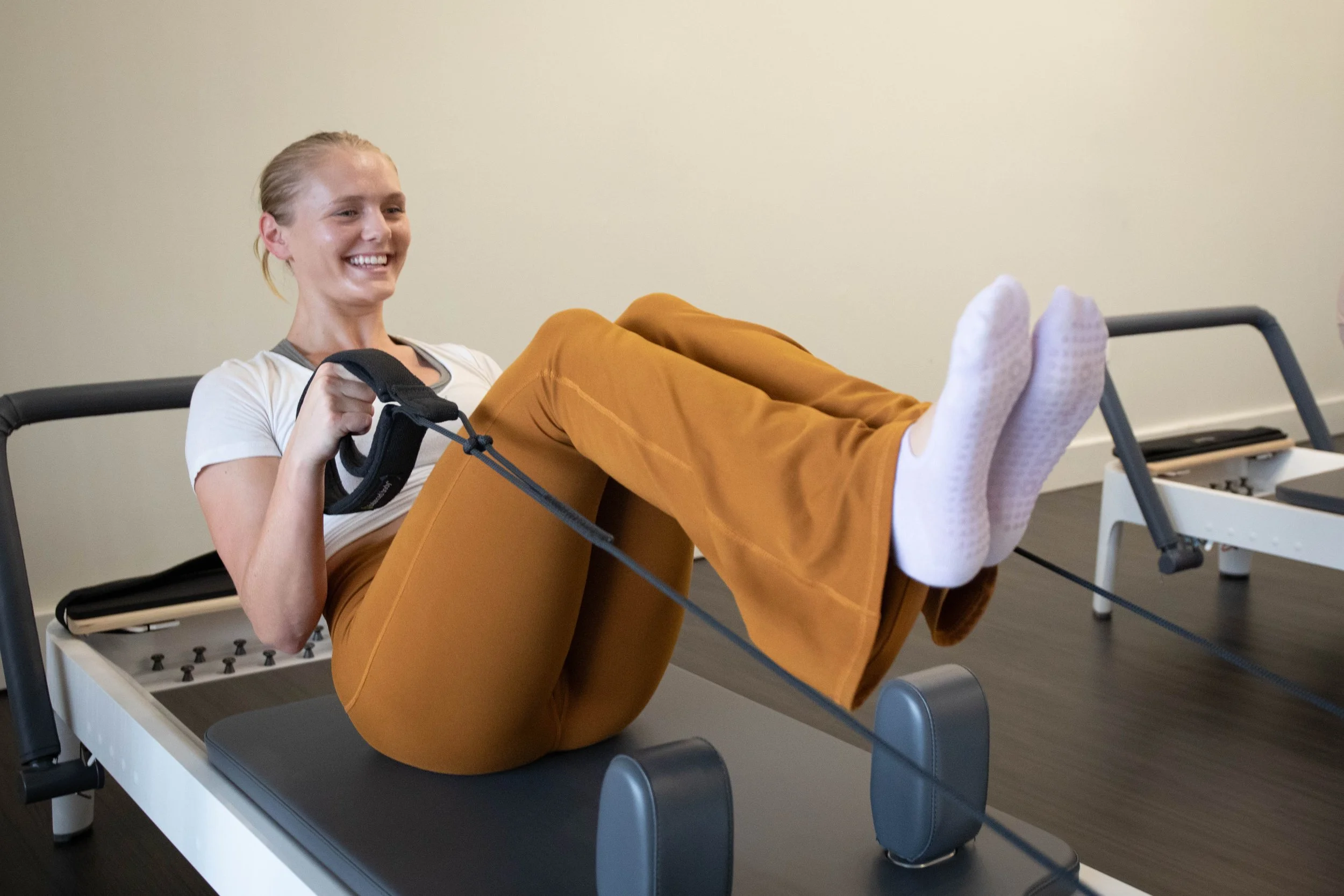 happy client doing reformer pilates exercises