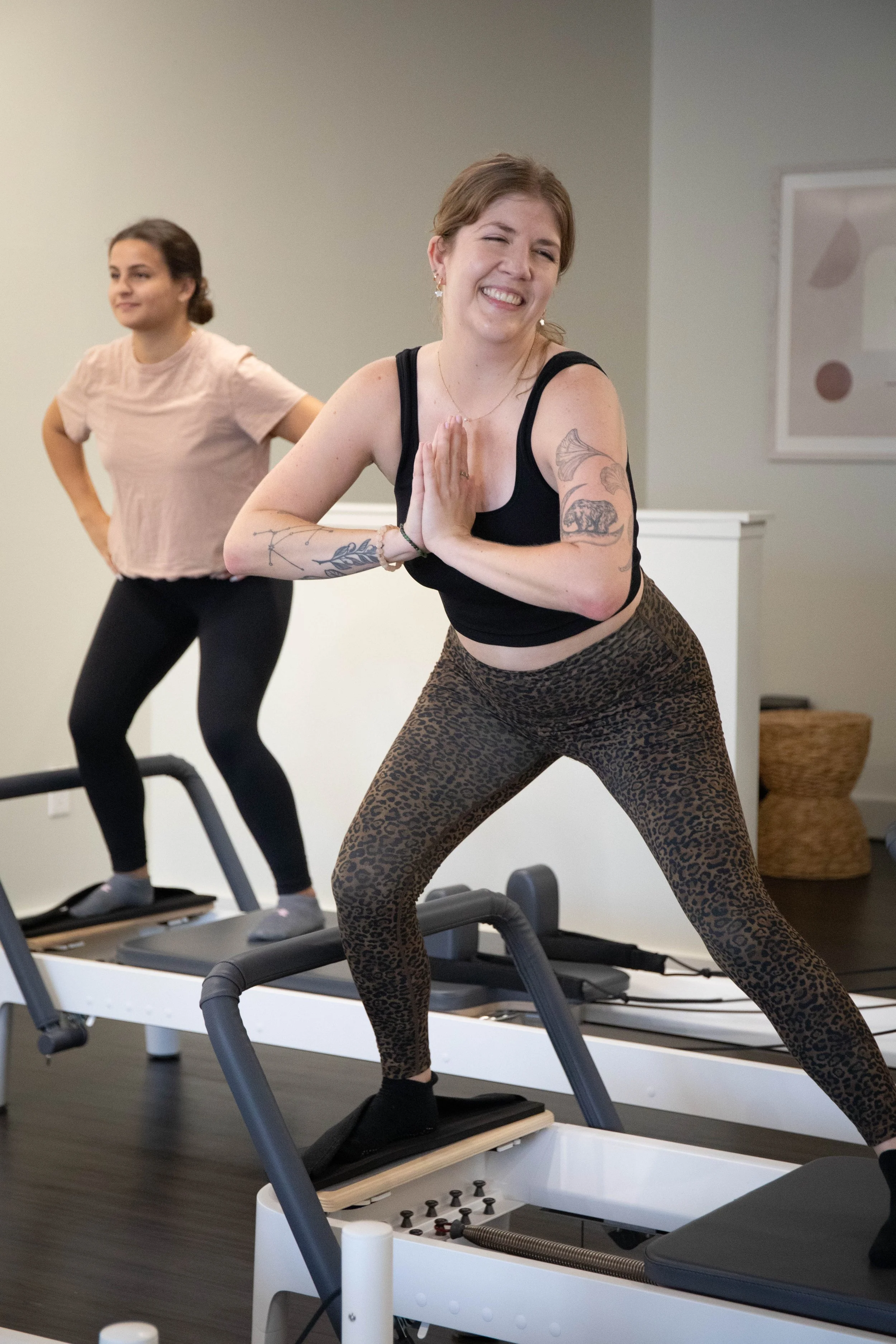 Pilates student smiling with hands pressed standing on a reformer