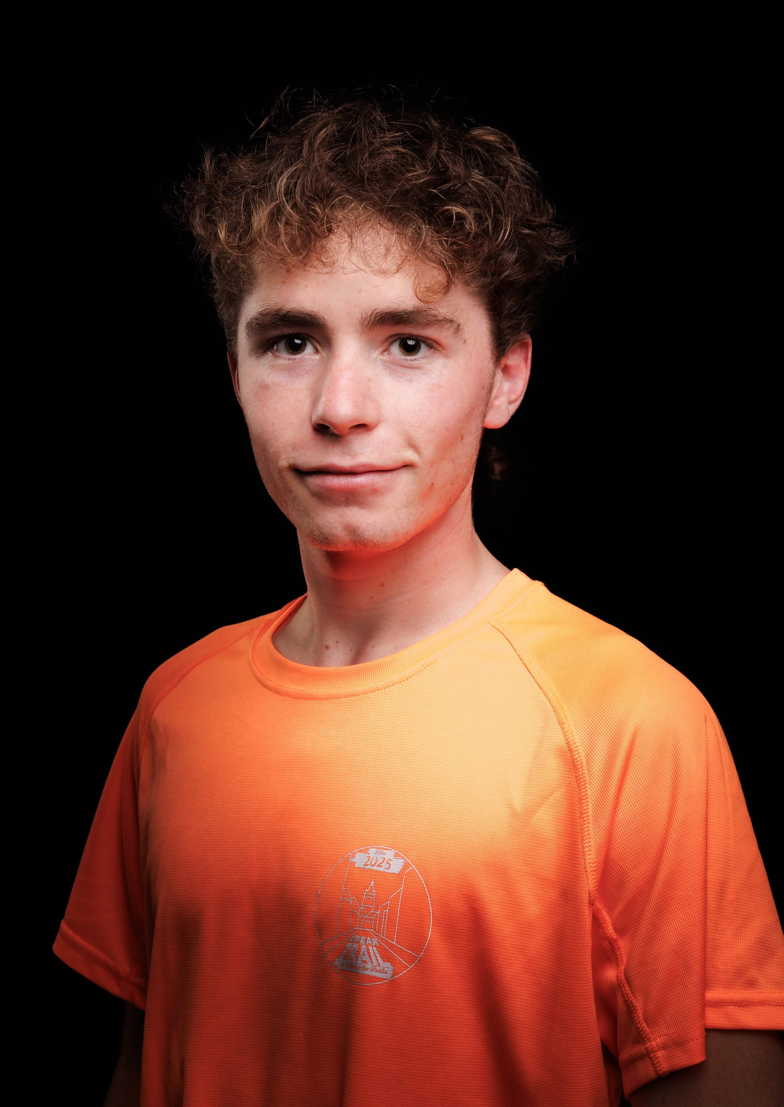 Runners prêts au départ d'une course, positionnés derrière la ligne de départ, dans une rue urbaine avec des bâtiments anciens en arrière-plan.