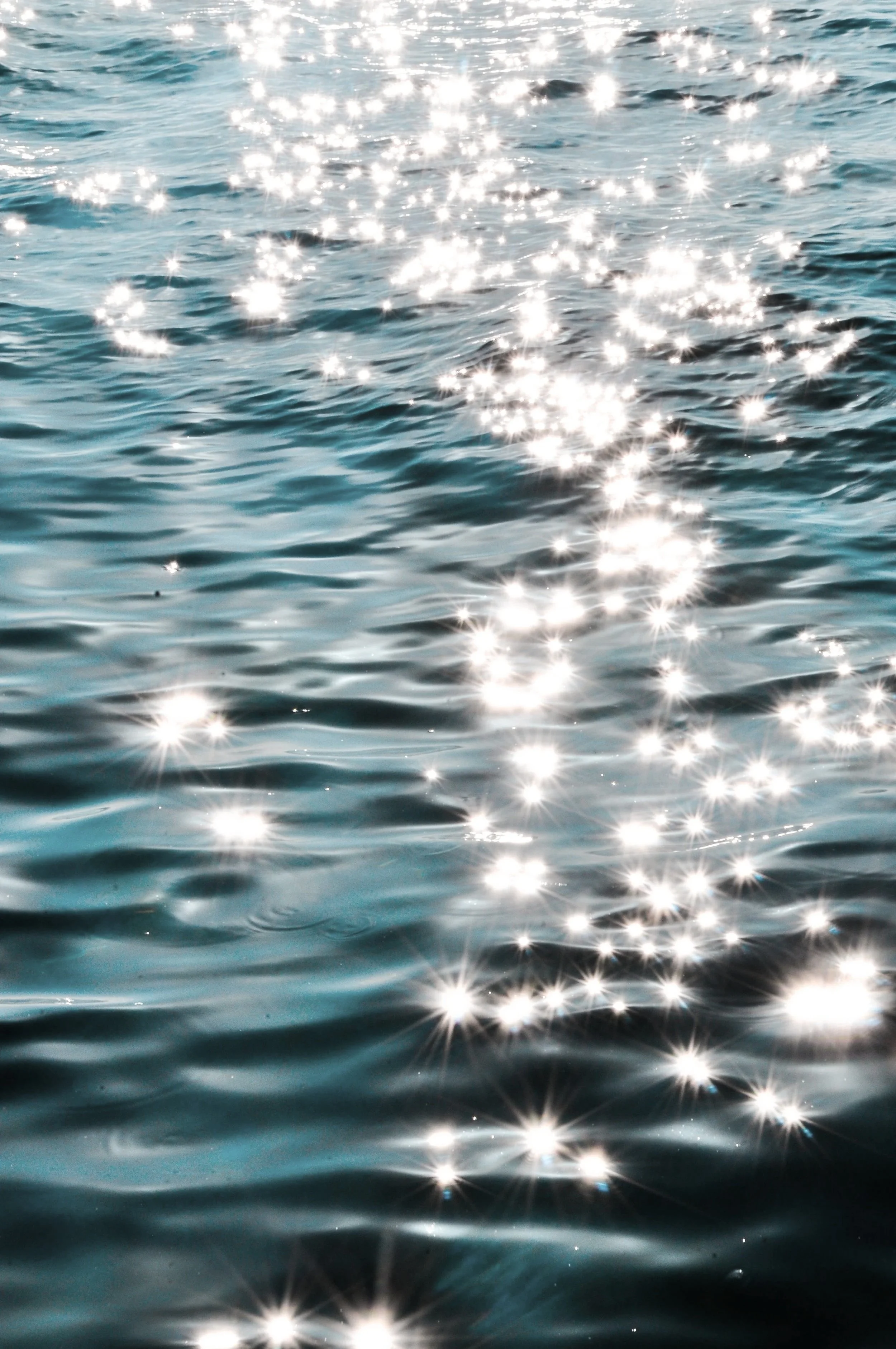 Sunlight reflecting off the surface of the ocean, creating sparkling bright spots on the water.