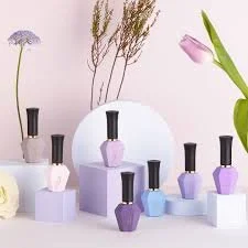 Collection of pastel-colored nail polish bottles arranged with flowers on a white surface.