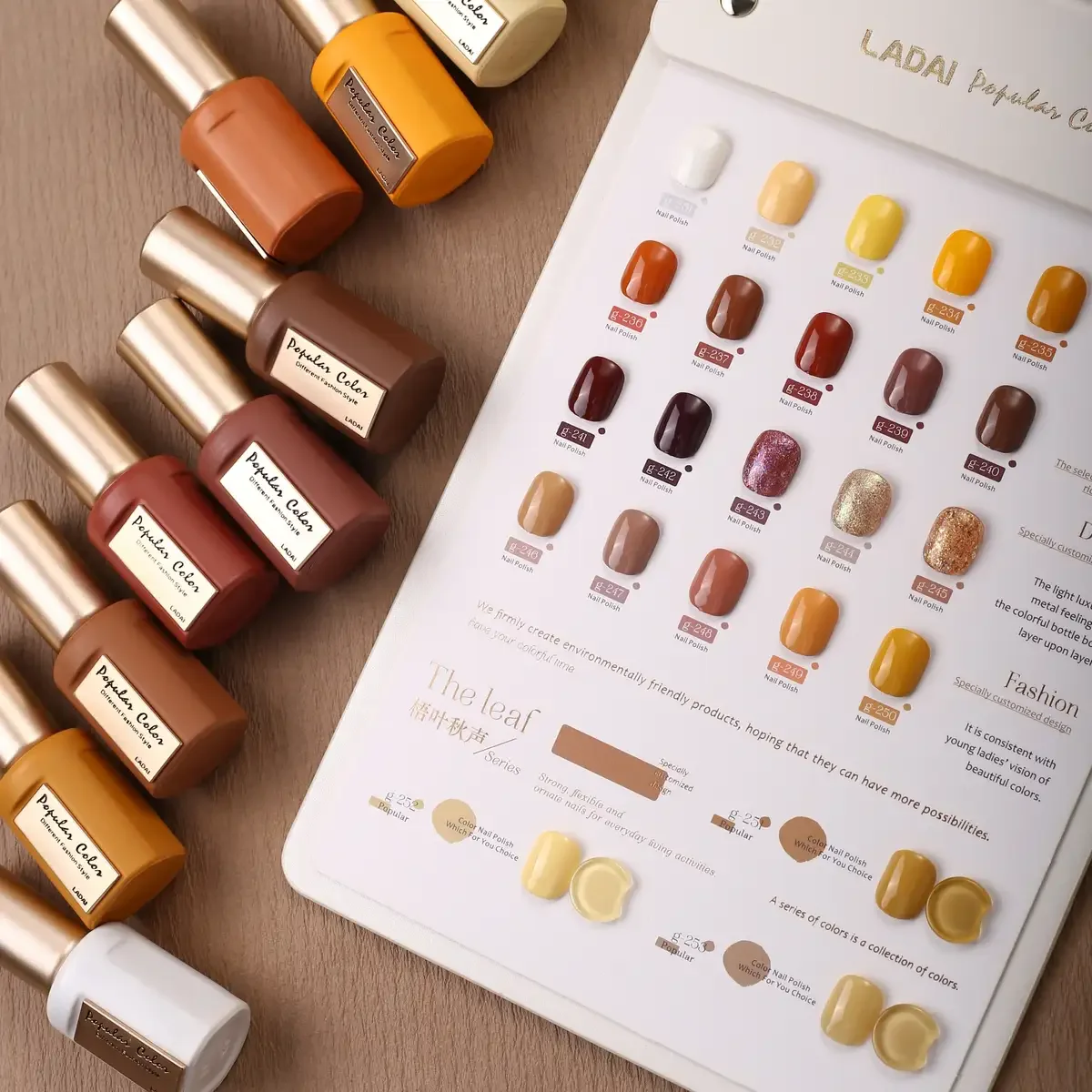 Display of nail polish bottles in various shades arranged on a sheet with corresponding color samples and descriptions, with additional bottles lined up beside the sheet.