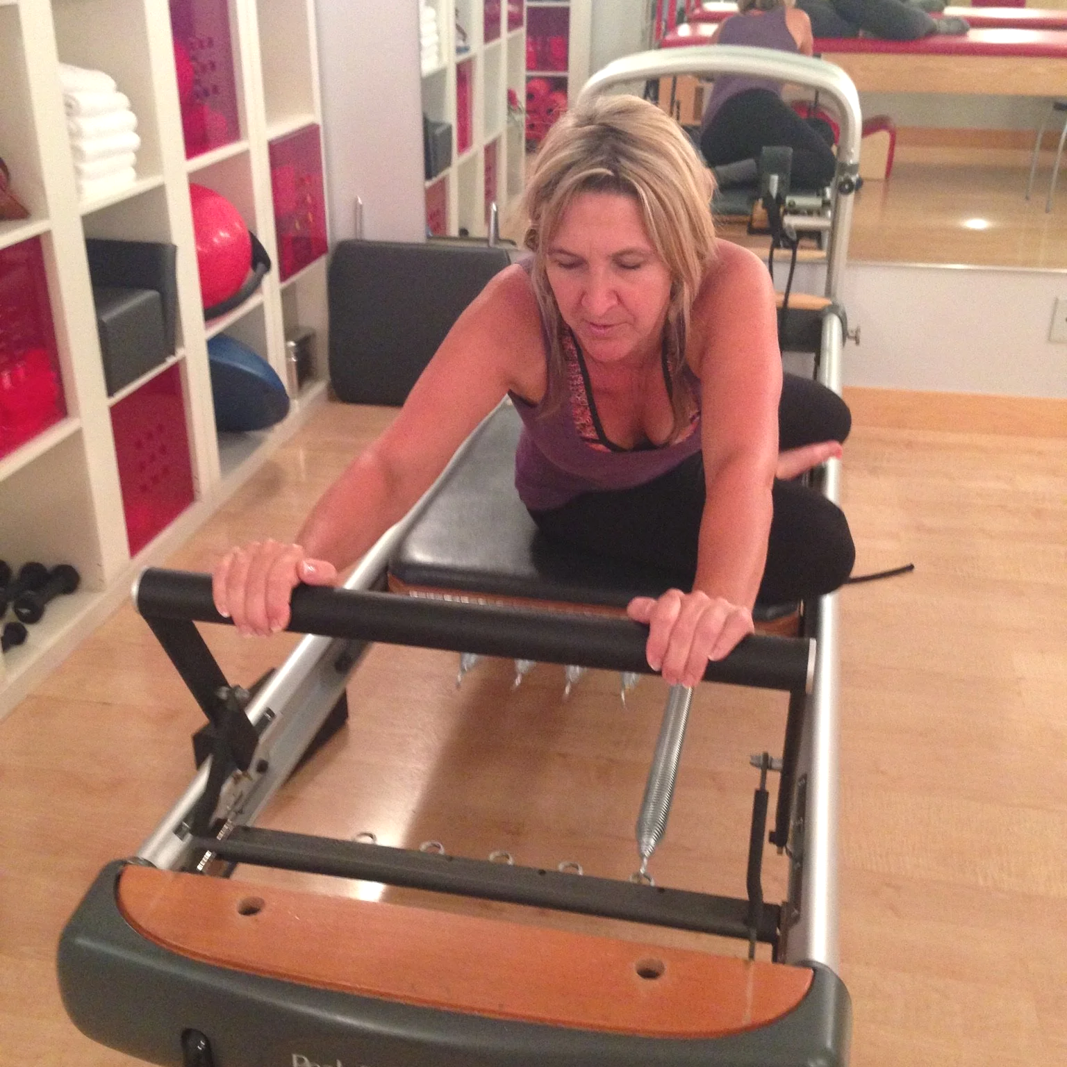 During a Pilates Private. Client is doing exercises on the reformer. Person performing an exercise on a Pilates reformer while pushing the carriage away.