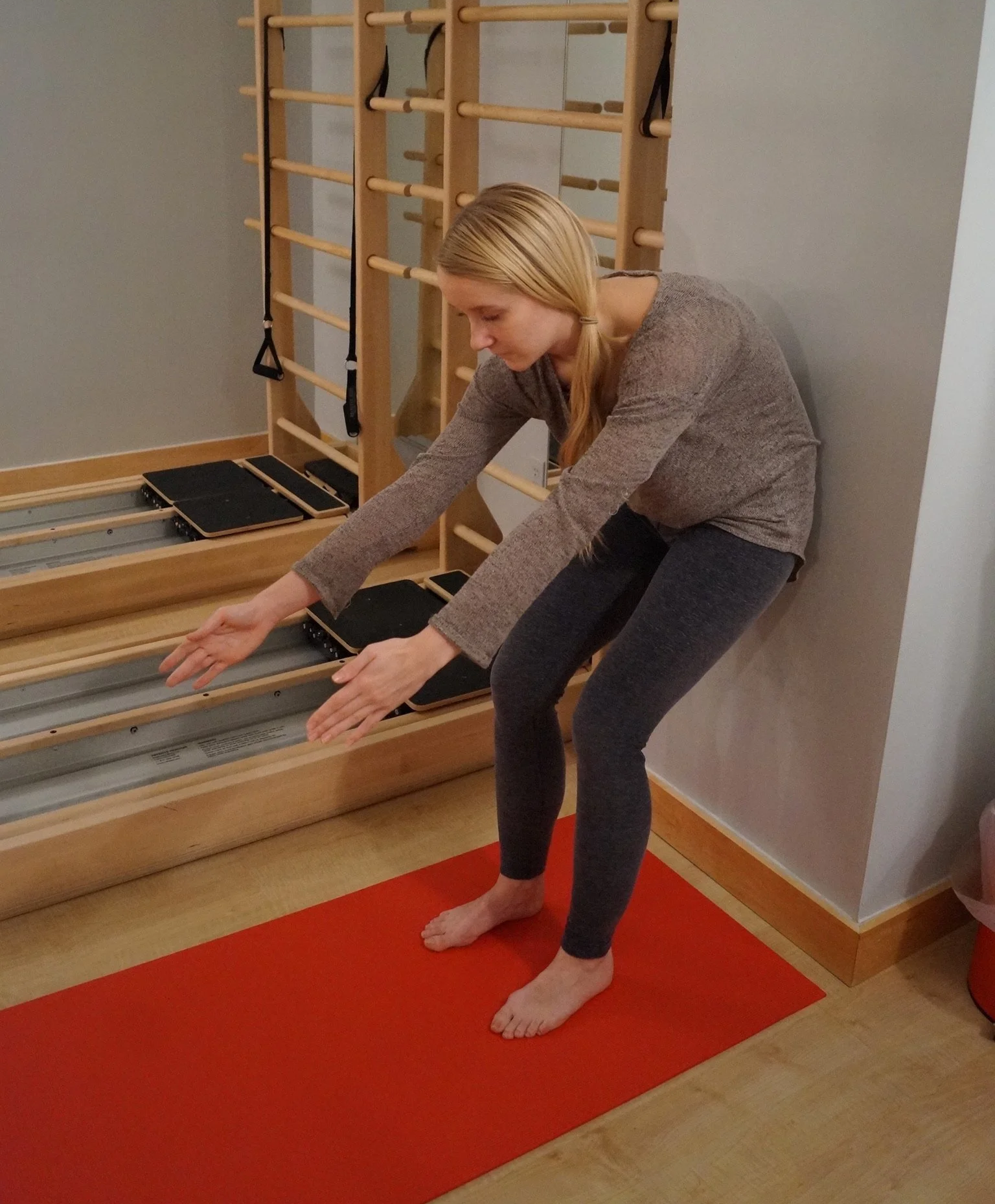 Patient is on a wall reaching arms forward and curving back forward in order to engage ab muscles.