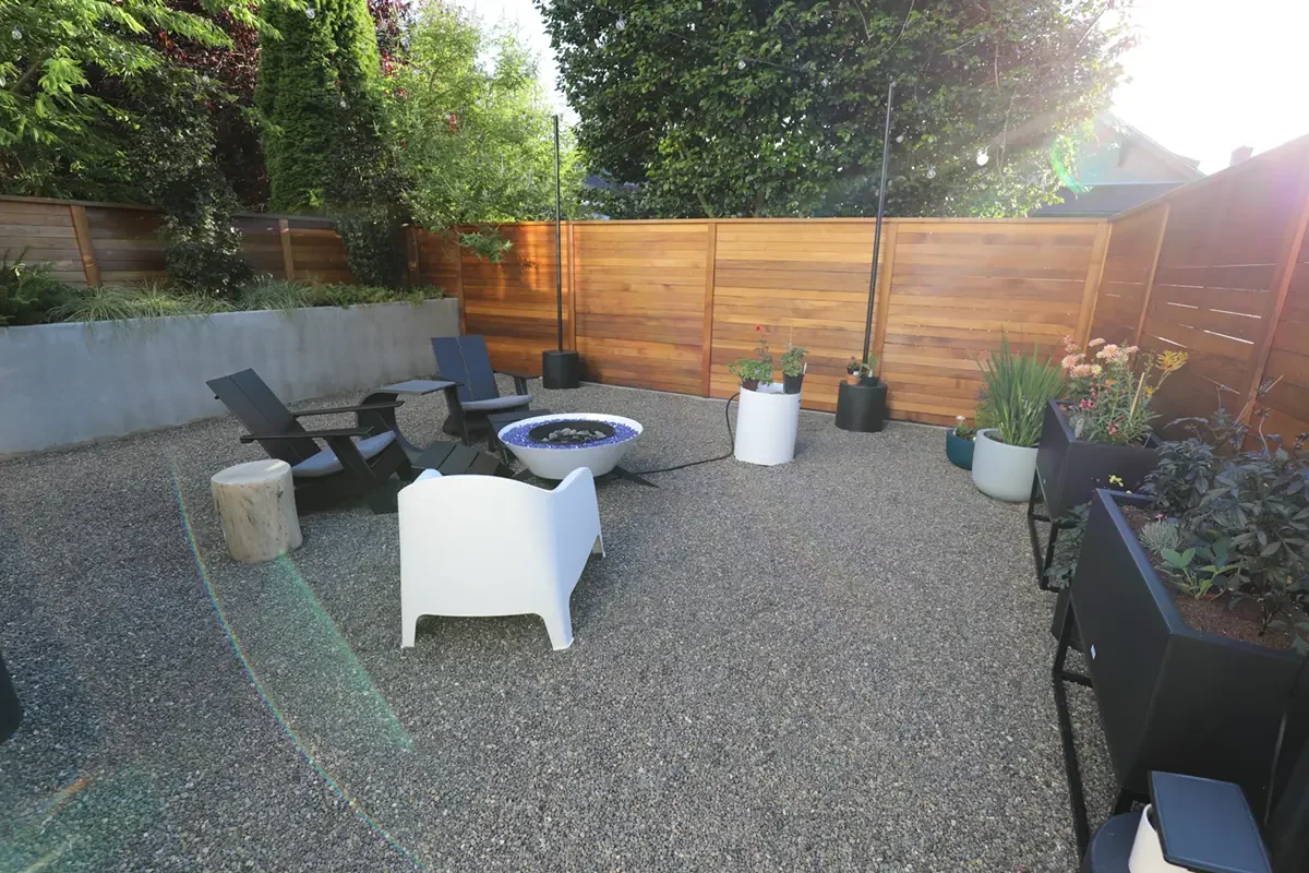 Backyard patio with outdoor seating, potted plants, and a privacy wooden fence.