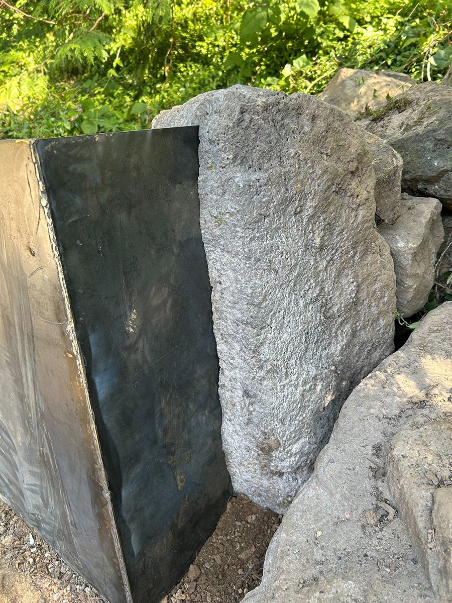 Large gray rocks outdoors with green foliage in the background.