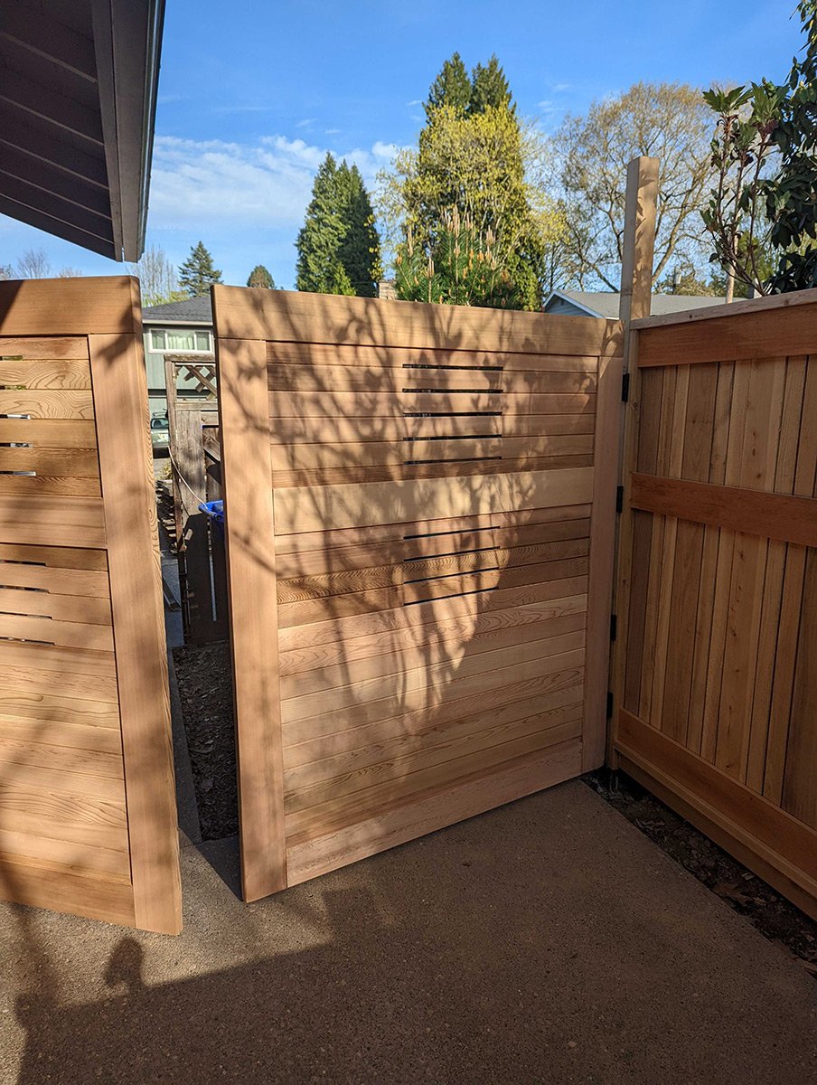 Wooden privacy fence panels with shadows cast by nearby trees on a sunny day