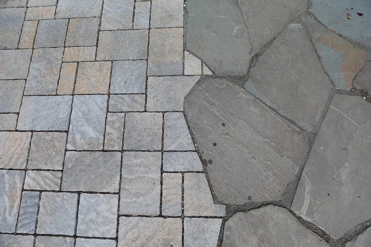 Close-up of a section of a paved pathway with square-shaped bricks and irregular-shaped stones.