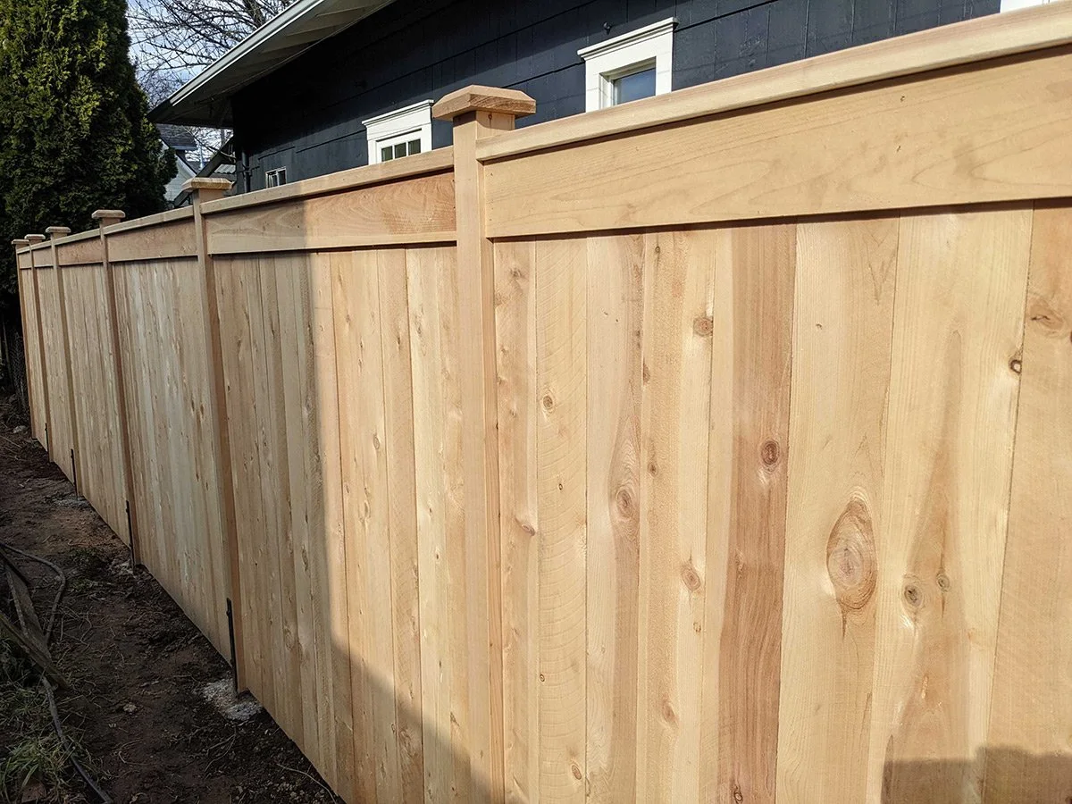 New wooden privacy fence along the backyard of a house.