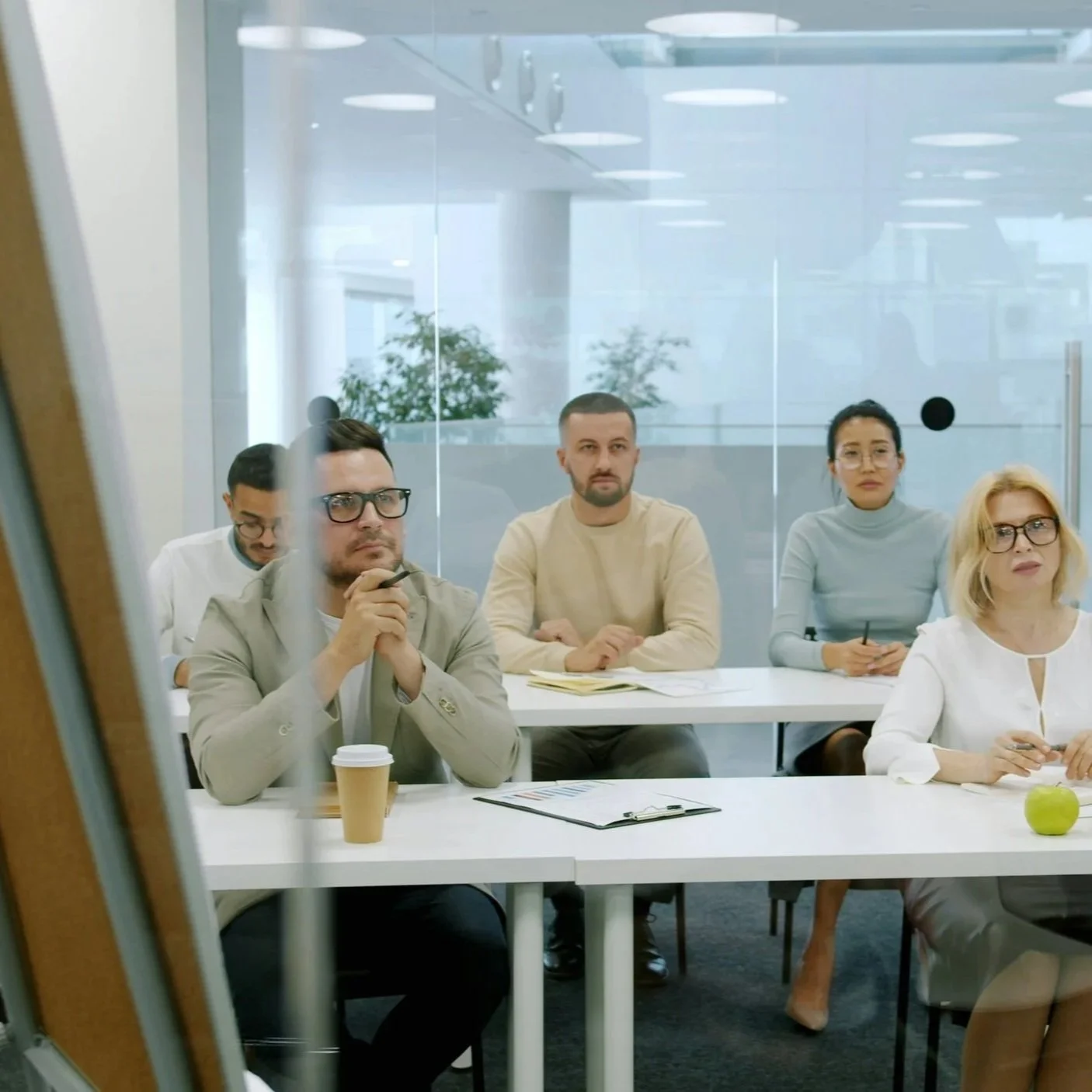Group of five diverse business professionals in a conference room, attentively listening during a meeting.