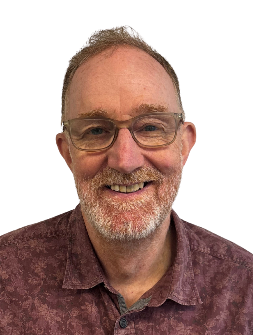 A smiling middle-aged man with gray hair and a beard, wearing glasses and a maroon patterned shirt, against a white background.