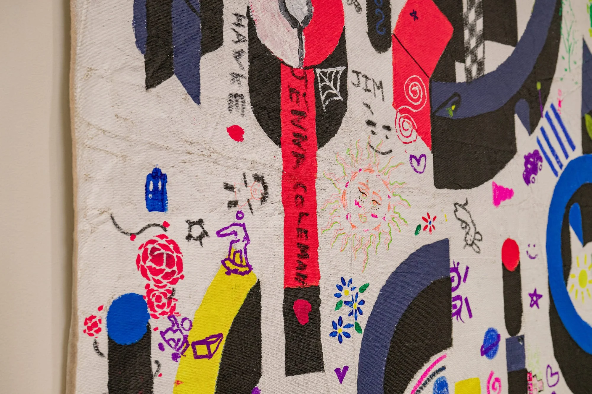 Colorful abstract artwork with various doodles and symbols, including a smiling sun with wavy rays, hearts, flowers, and text written in different colors and styles on a white background.