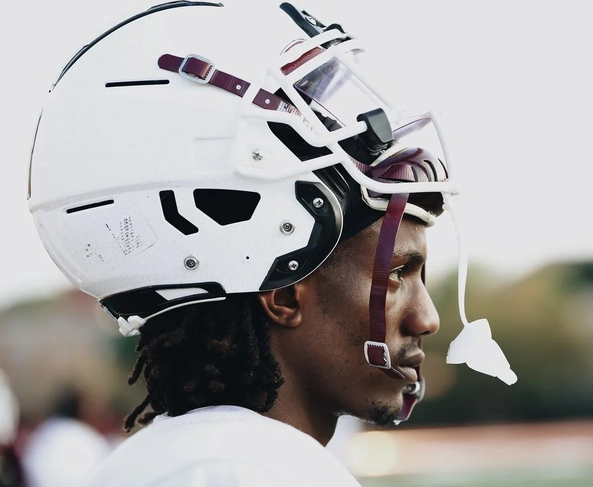 A Side profile of a football player wearing a white helmet with a face mask and eye goggles.