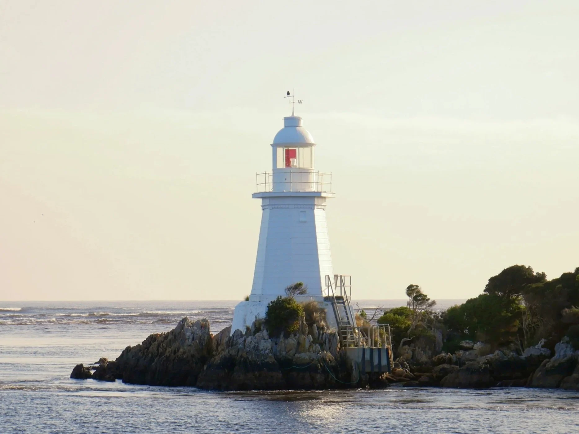 White lighthouse on a rocky shore overlooking the ocean