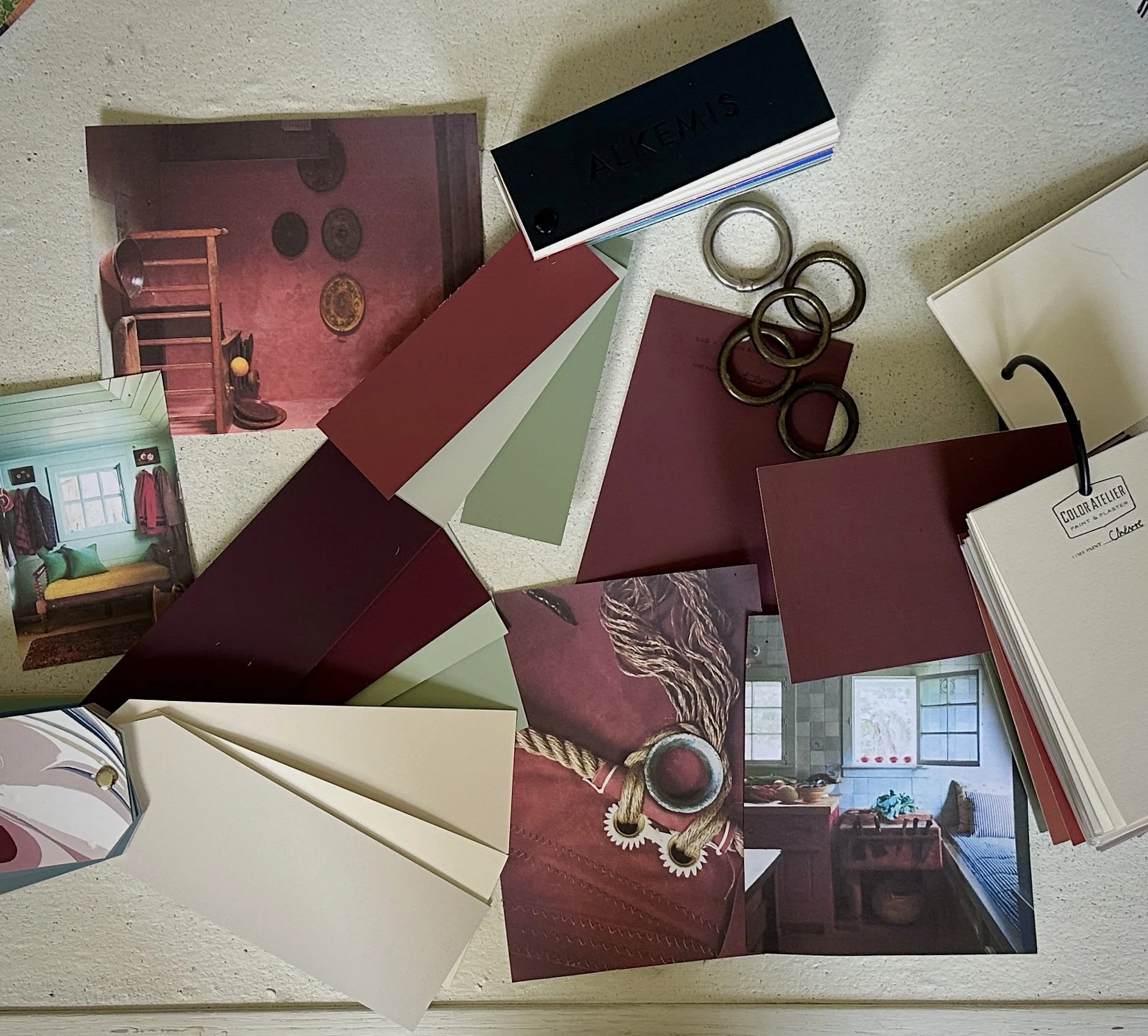 Color palette, fabric swatches, photographs of interior rooms, and rings on a white surface.
