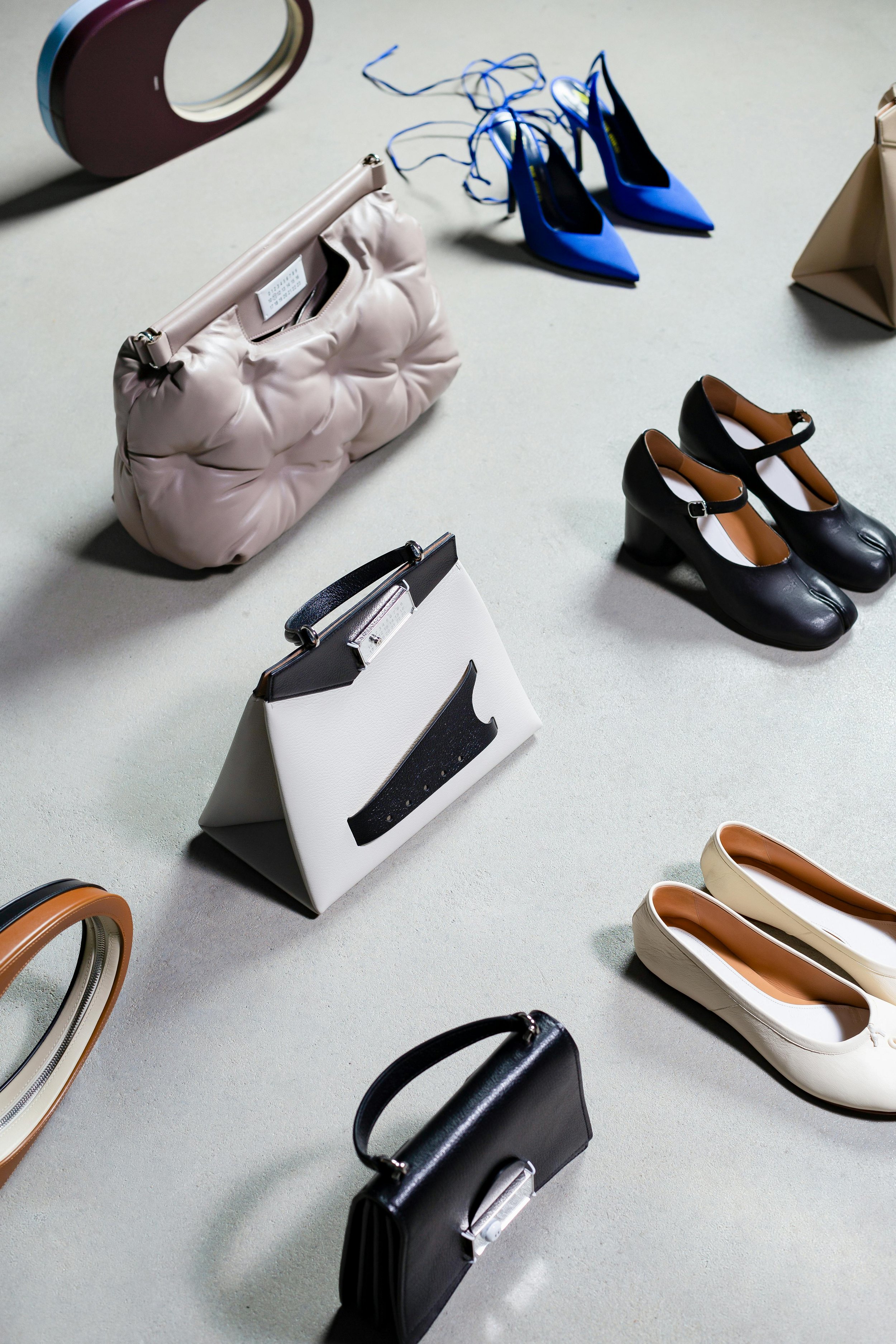 Assorted designer handbags, shoes, and accessories arranged on a light-colored surface.