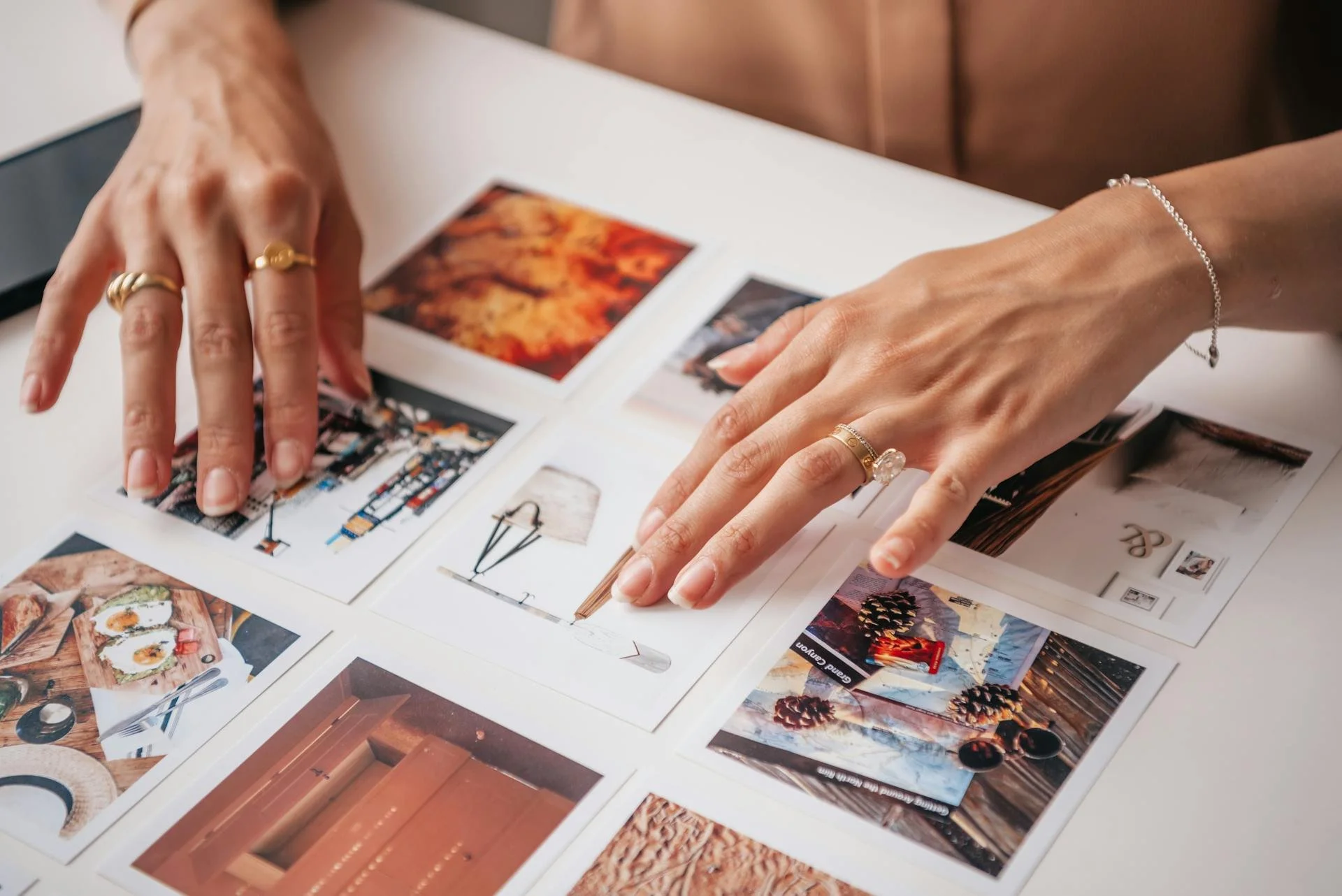Person arranging printed photographs on a white surface.