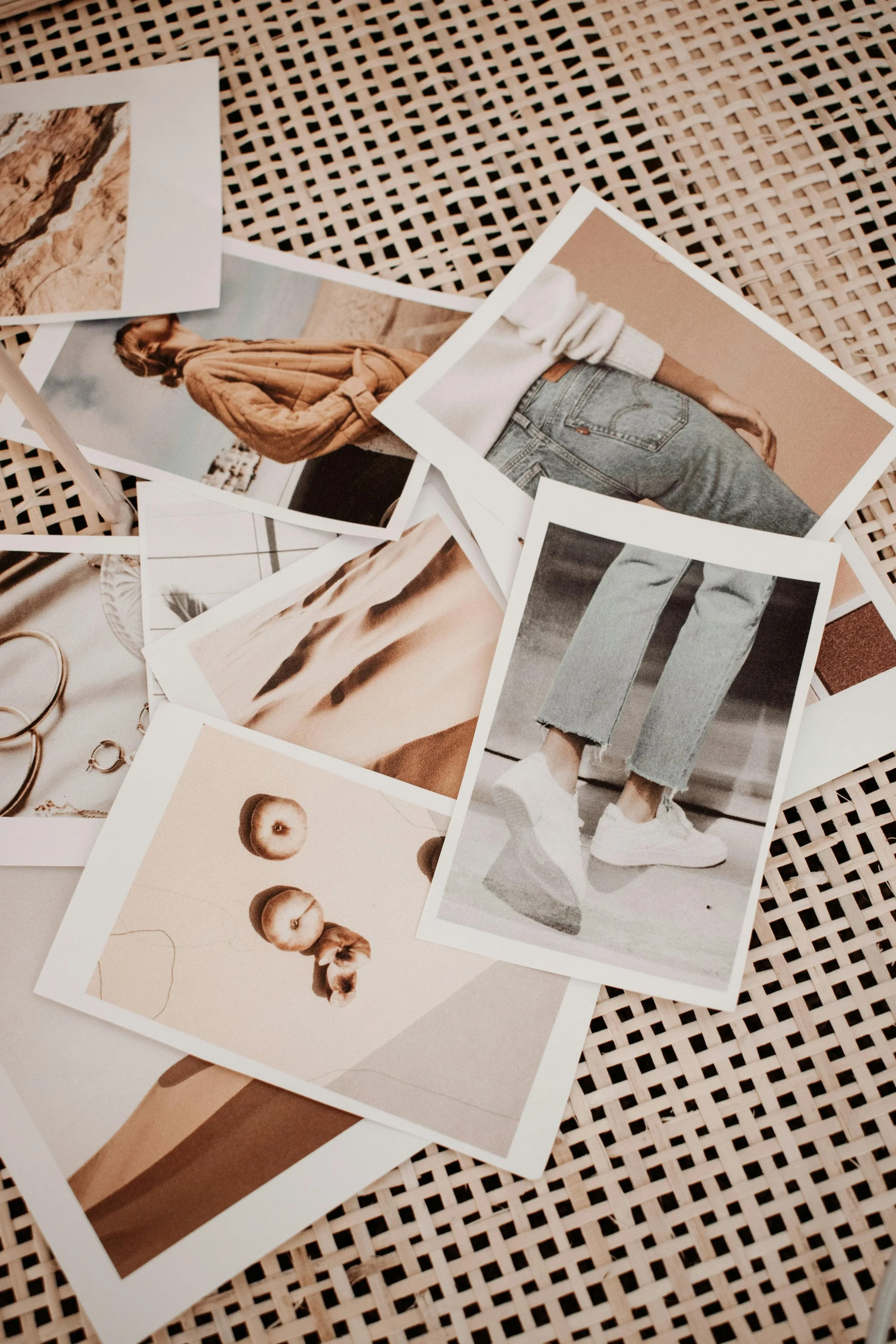 Collection of photographs scattered on a lattice surface, featuring fashion, jewelry, desert landscape, and abstract images.