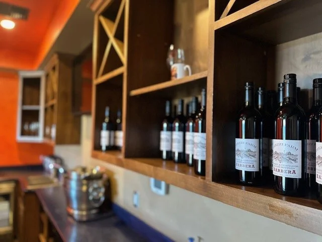 Wooden wine rack with bottles of wine on shelves in a restaurant or bar setting.